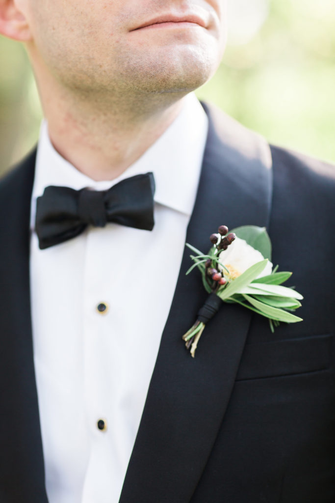Grooms boutonniere with white ranunculus, olive, berries, and rosemary