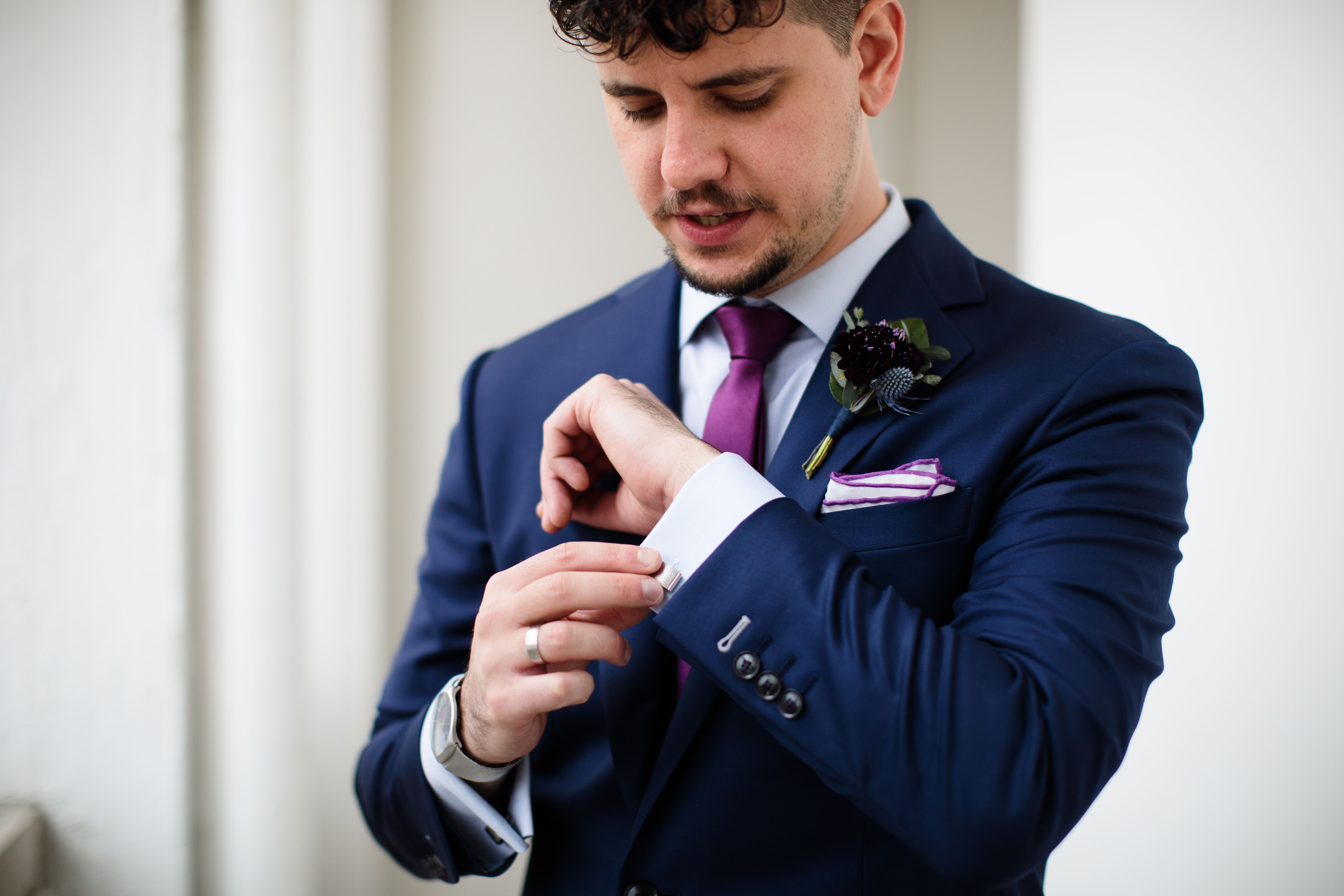 groom in navy suit with plum tie, burgundy boutonniere