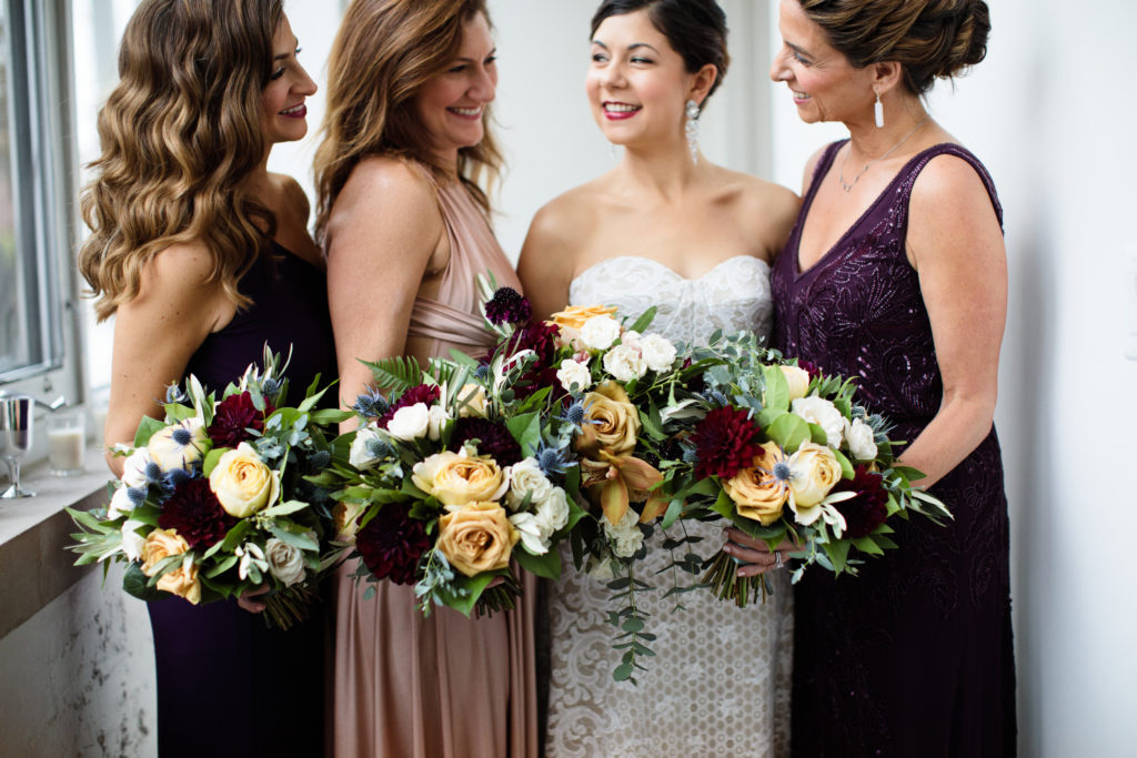 bouquets held by wedding party in burgundy, blush, eggplant bridesmaids' dresses