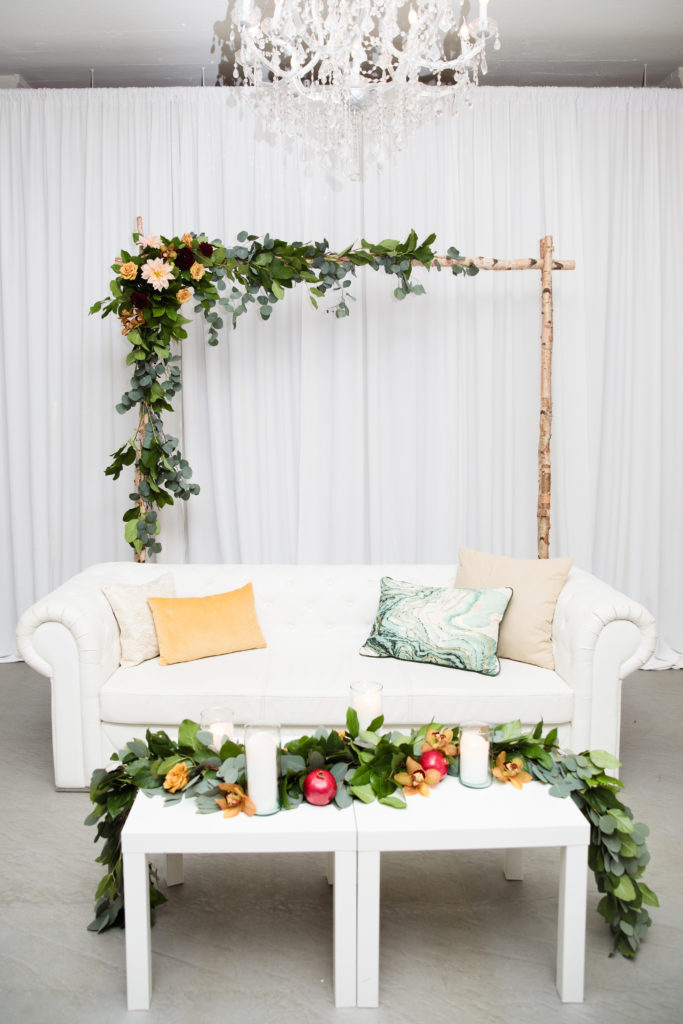 ceremony arch behind lounge area with garland on table