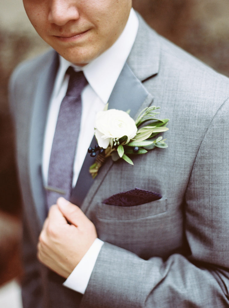 groom with white ranunculus boutonniere