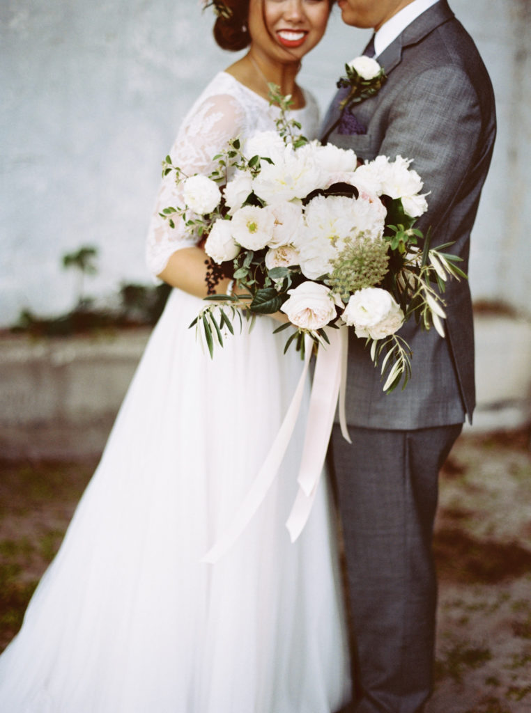 bride and groom with spring bouquet in blush and white