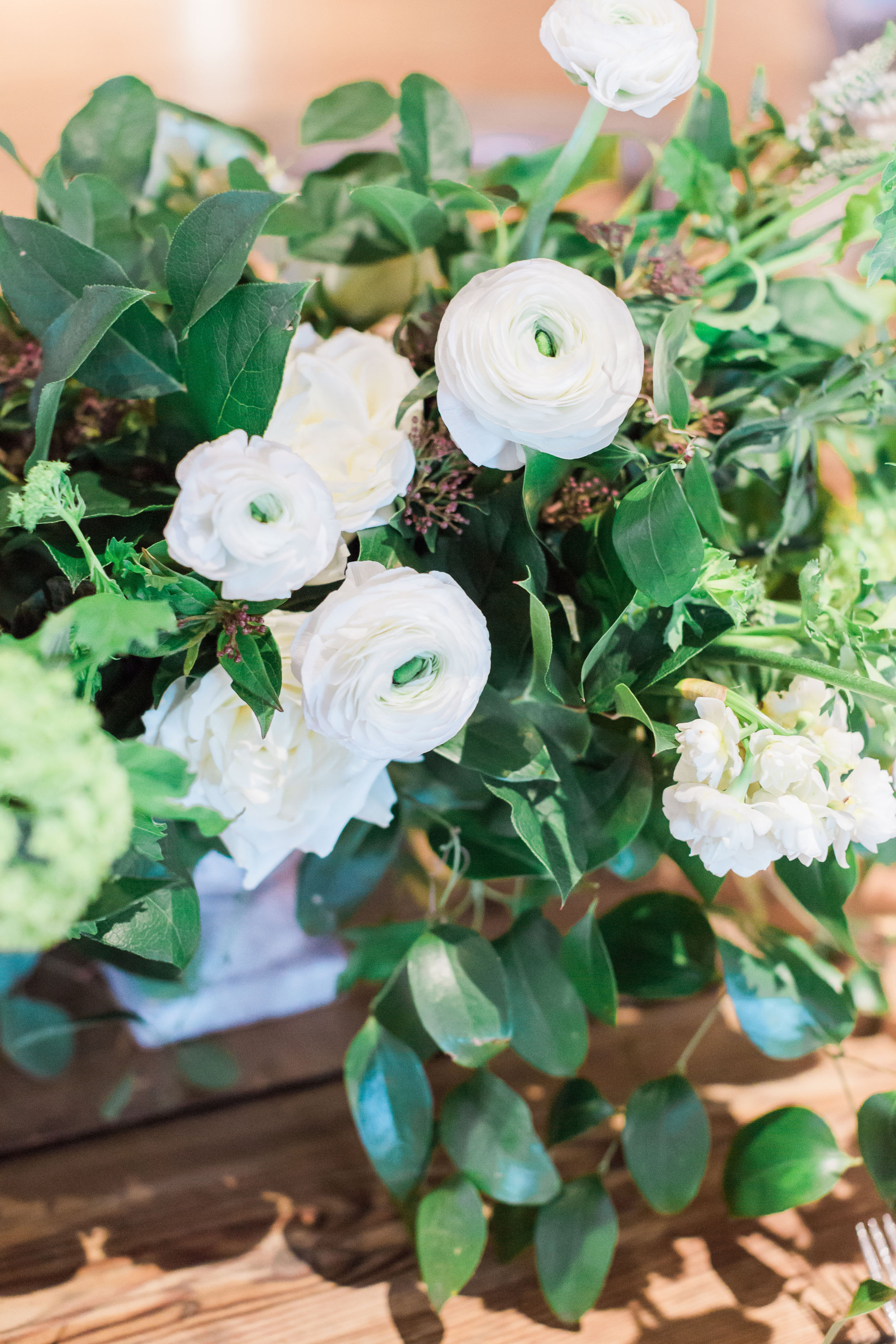 Winter wedding centerpiece with Clooney ranunculus, Southern smilax, and snowball viburnum.