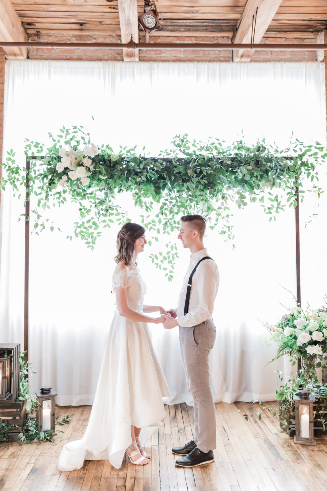 Wedding arch with green foliage and white flowers with bride and groom