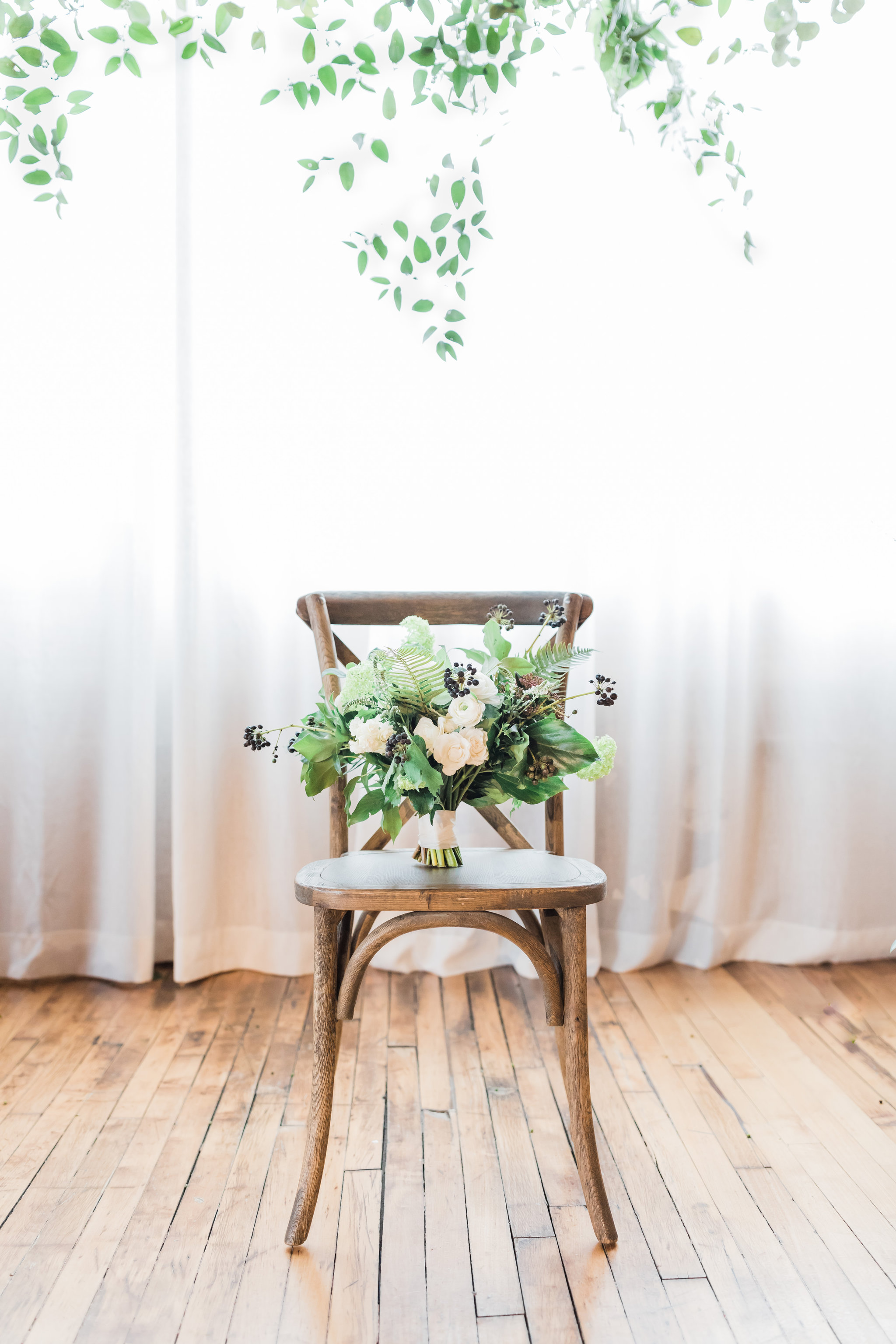 Green and white winter wedding bouquet on chair.