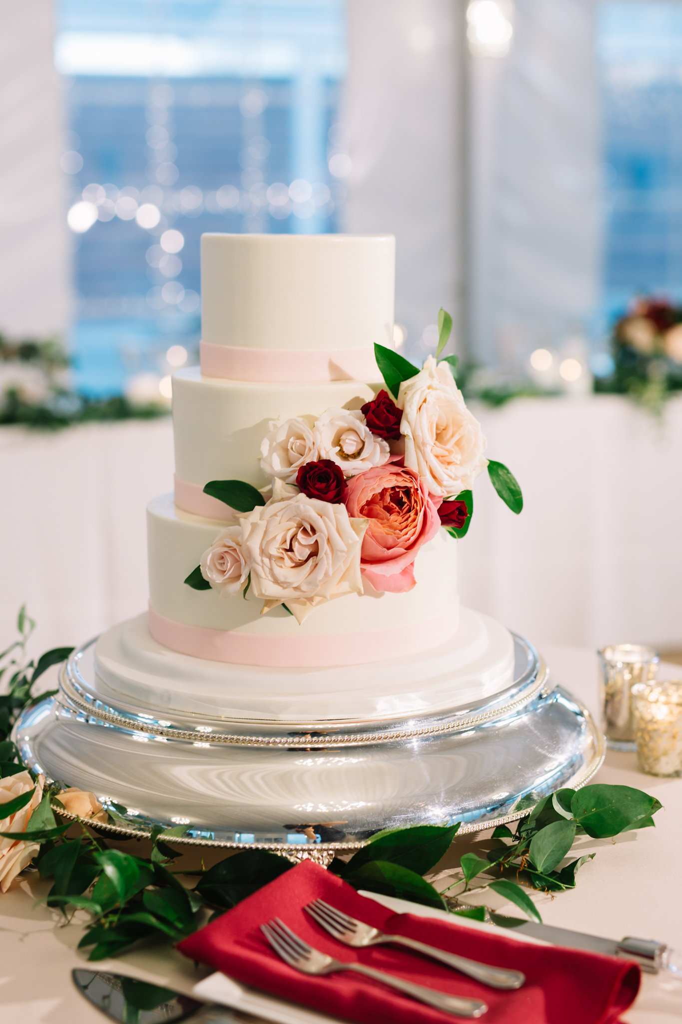 Wedding cake decorated with cream, blush, and coral roses.