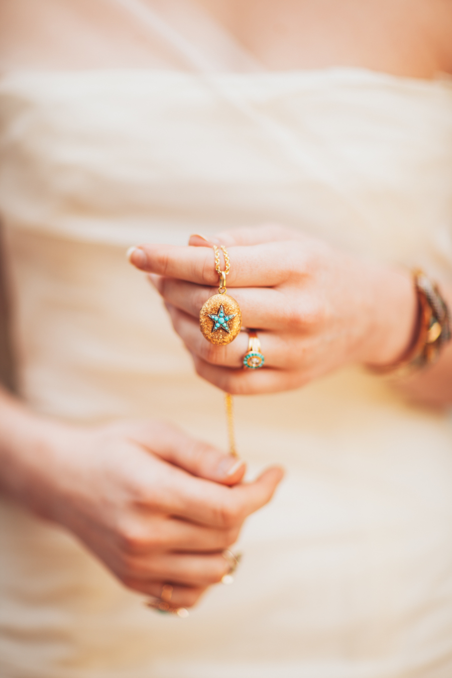 Bride holding turquoise necklace with star and ring.