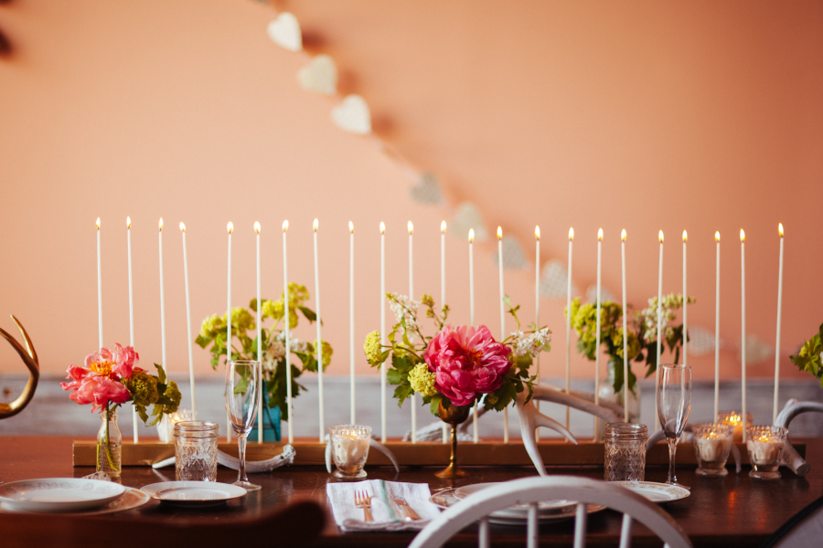 wedding reception table decor with taper candles and low garden loose arrangements with pink peonies. 