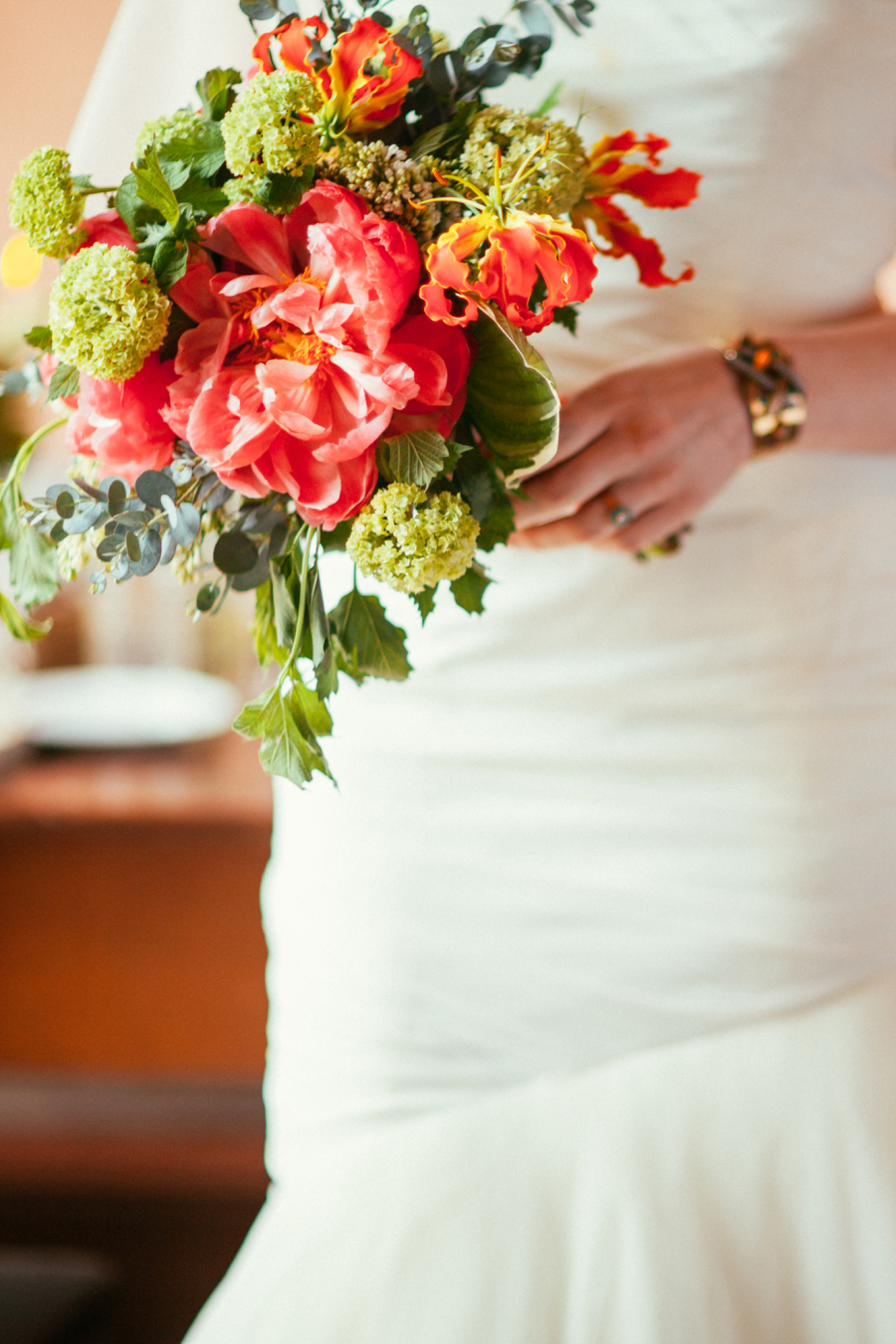 Bride holding bouquet of pink peonies, snowball viburnum, gloriosa lilies.