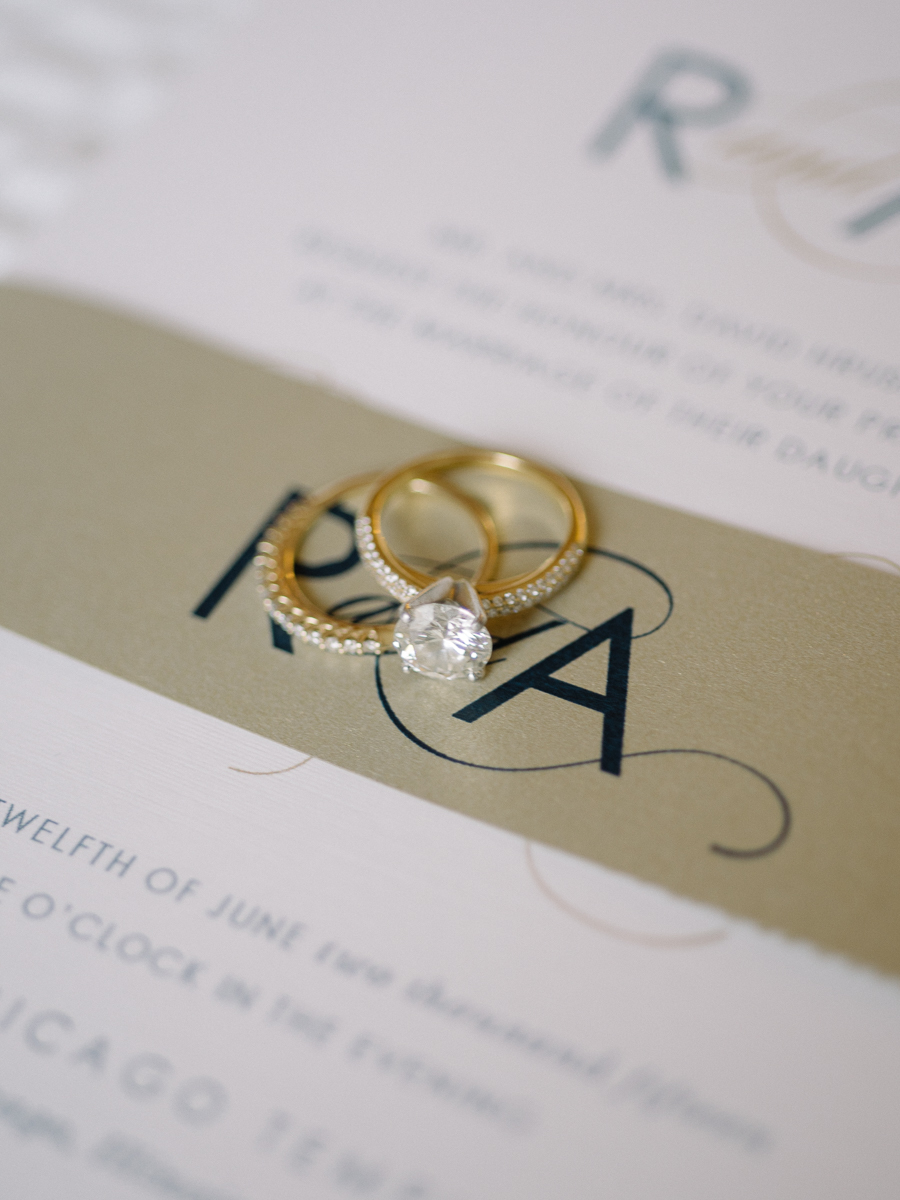 Gold wedding rings over wedding invitation.