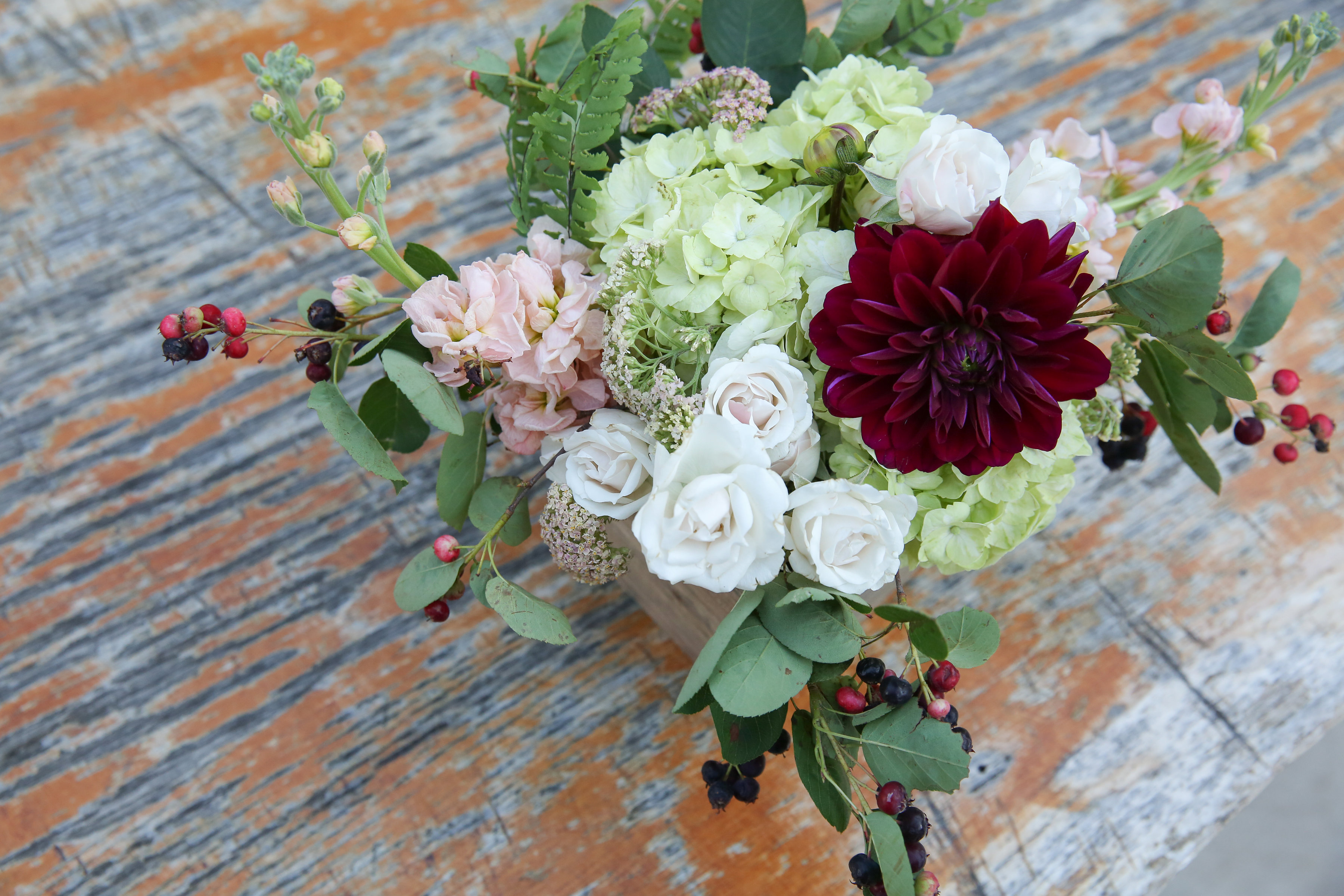 Early summer wedding loose arrangement of dahlias, stock, white majolica, berries, and green hydrangea.