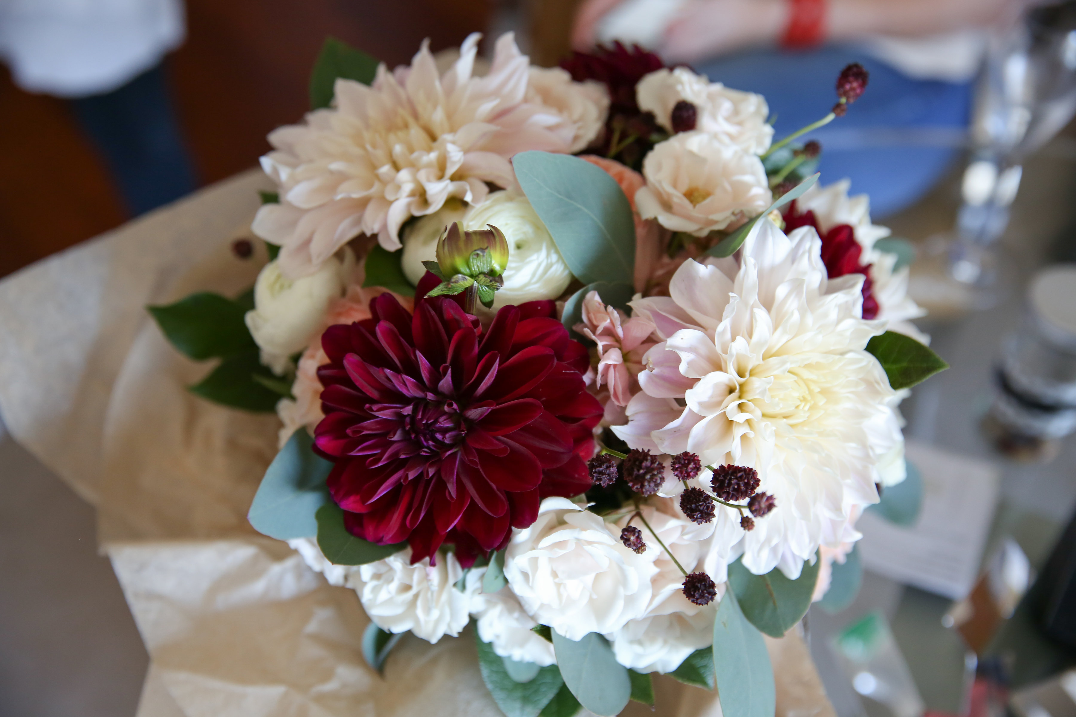 Early summer wedding arrangement of dahlias and berries in wine, pale blush, and ivory.
