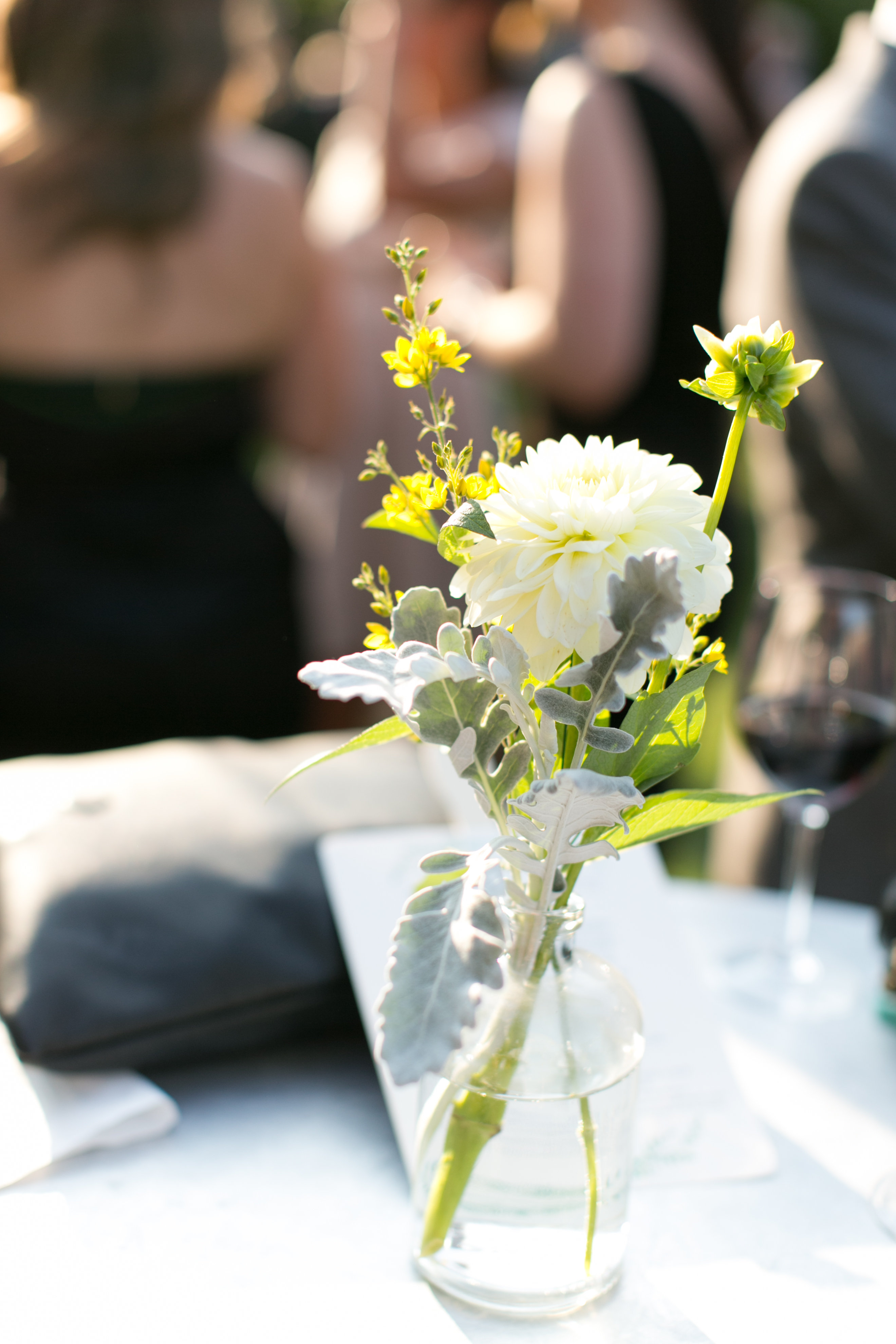 Miniature wildflower arrangements with ivory dahlia for late summery outdoor ceremony.
