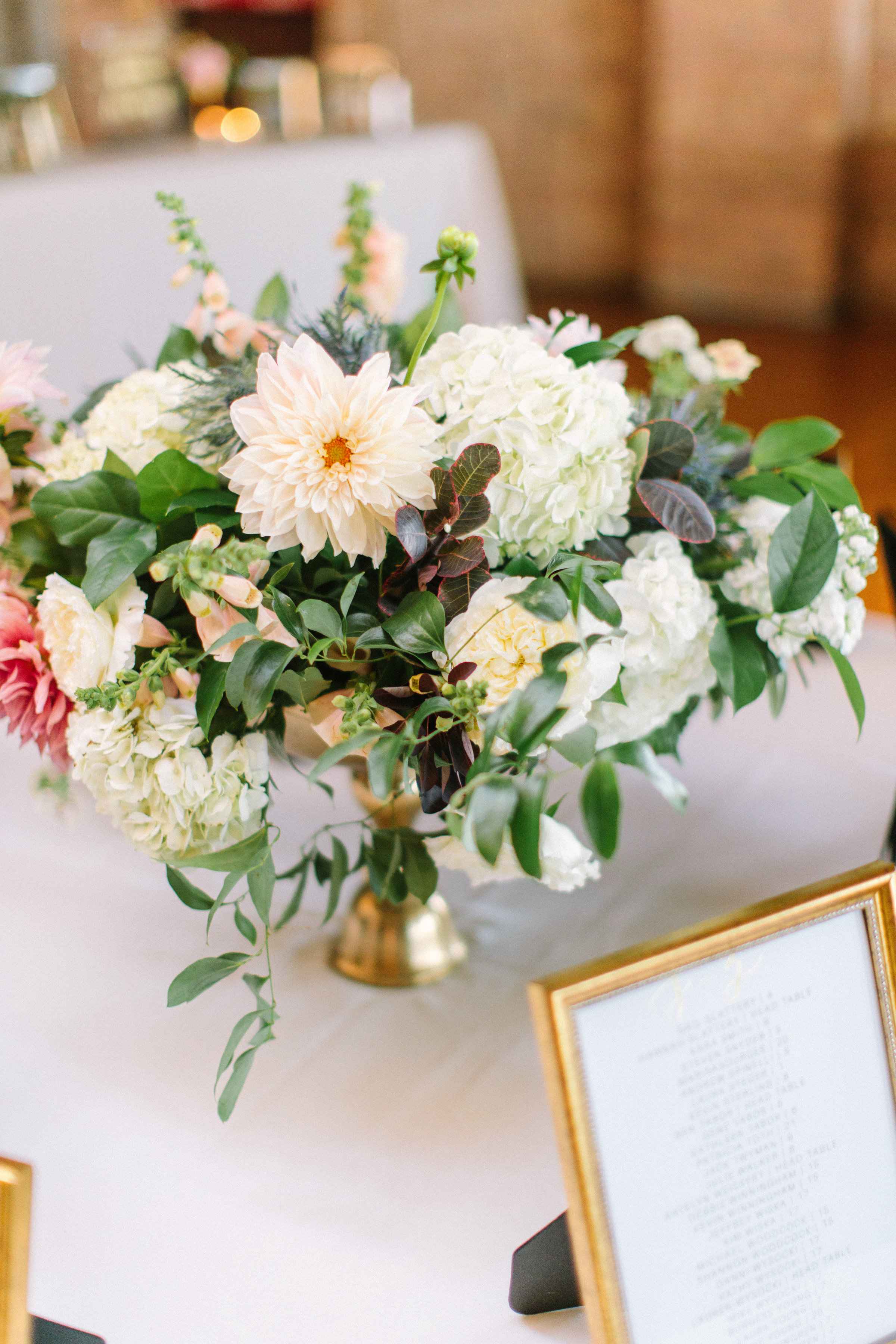 Welcome table arrangement at fall wedding at Bridgeport Art Center with white hydrangea and dahlias.