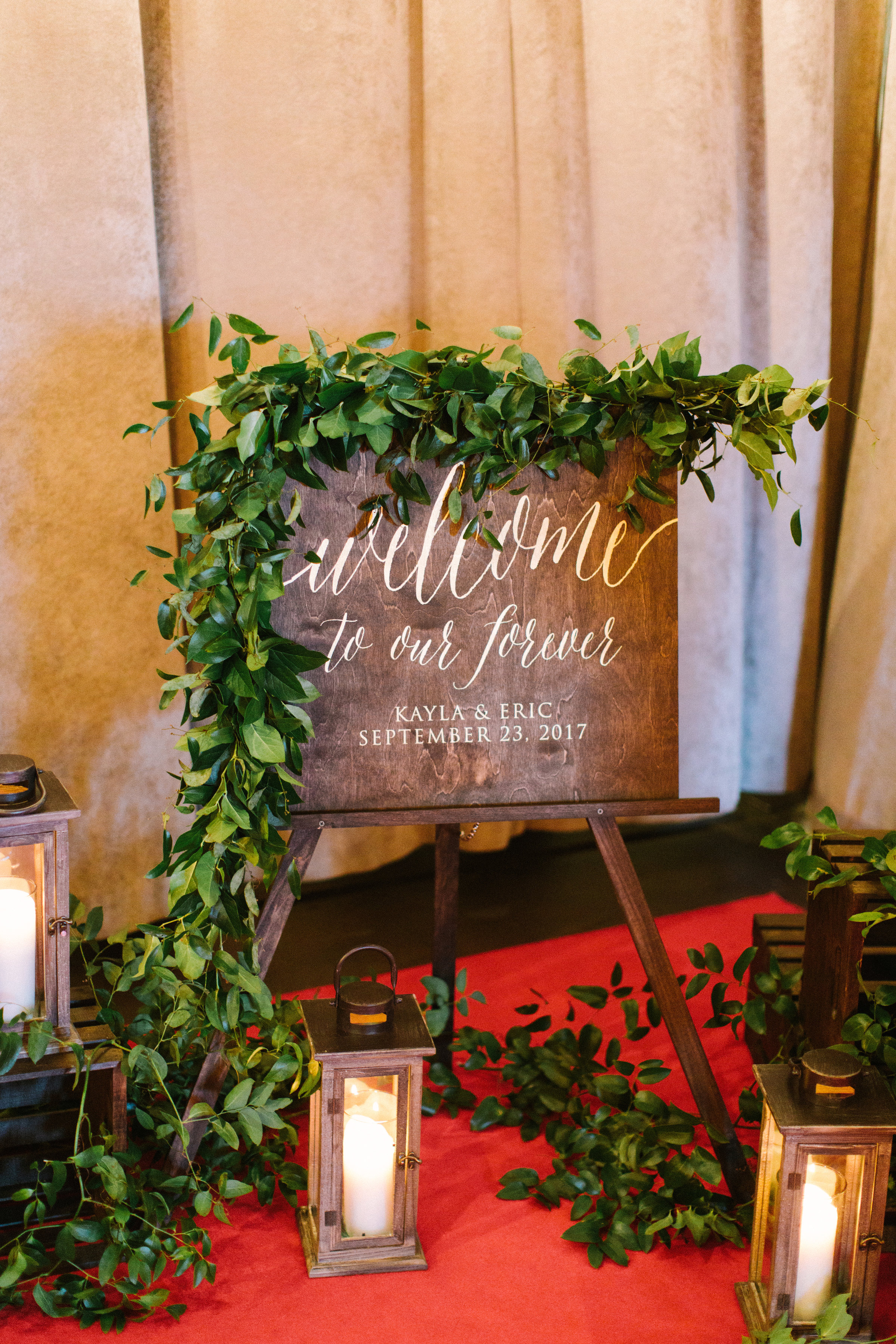 Entry vignette at Bridgeport Art Center wedding in Chicago with welcome sign on easel, lanterns, and foliage garlands.