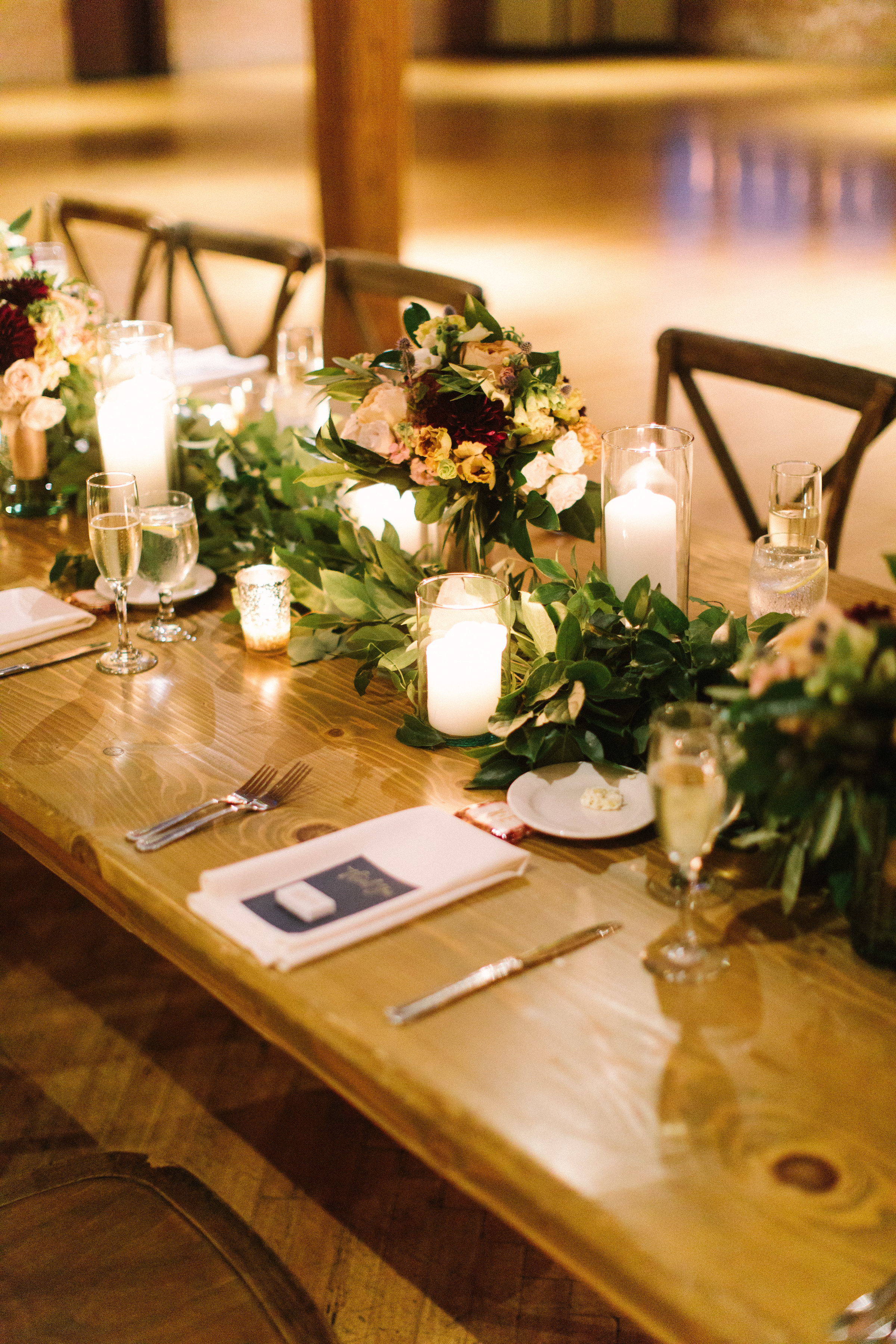 Farm table with garland, candles, and wedding bouquets