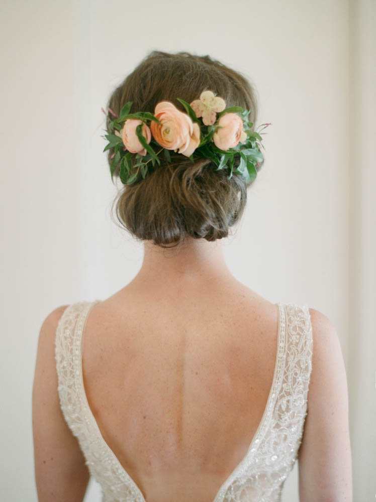 Summer bride with up-do and hair flowers: peach ranunculus and jasmine.