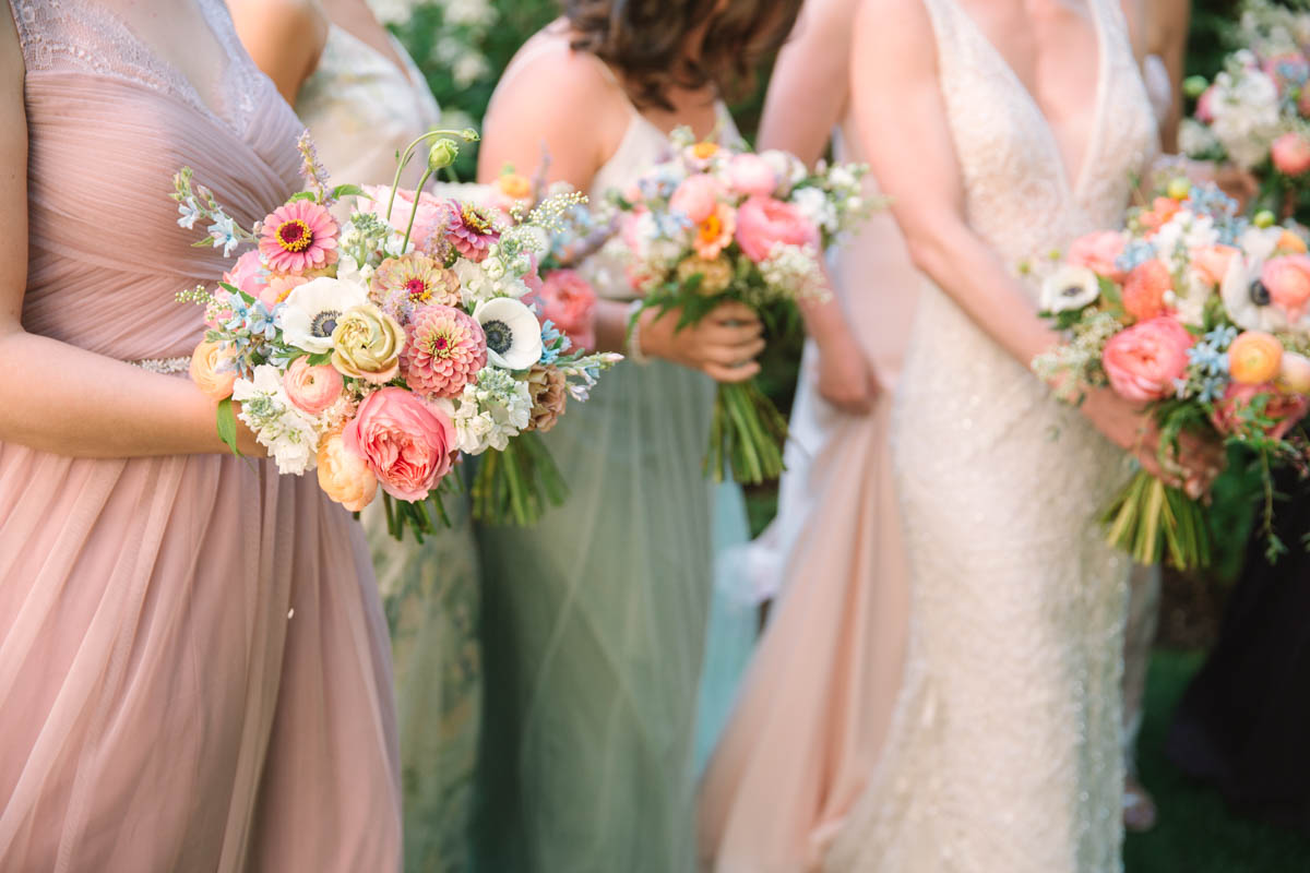 Bridesmaids with romantic colorful garden bouquets of anemones, zinnias, and roses.