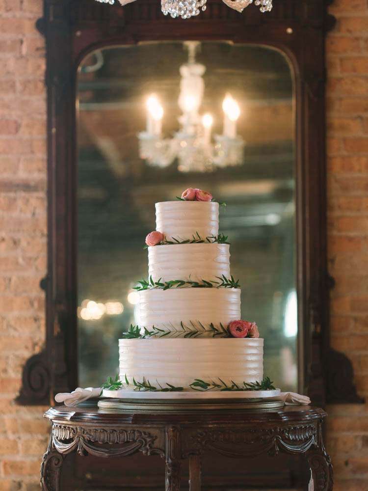 4-tiered wedding cake with foliage and pink ranunculus at Salvage One.