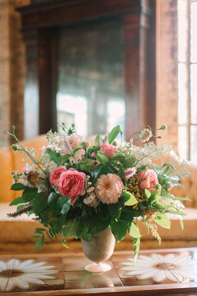 Summer wedding centerpiece of pink garden roses, blush dalhias, fern, and loose flowers.