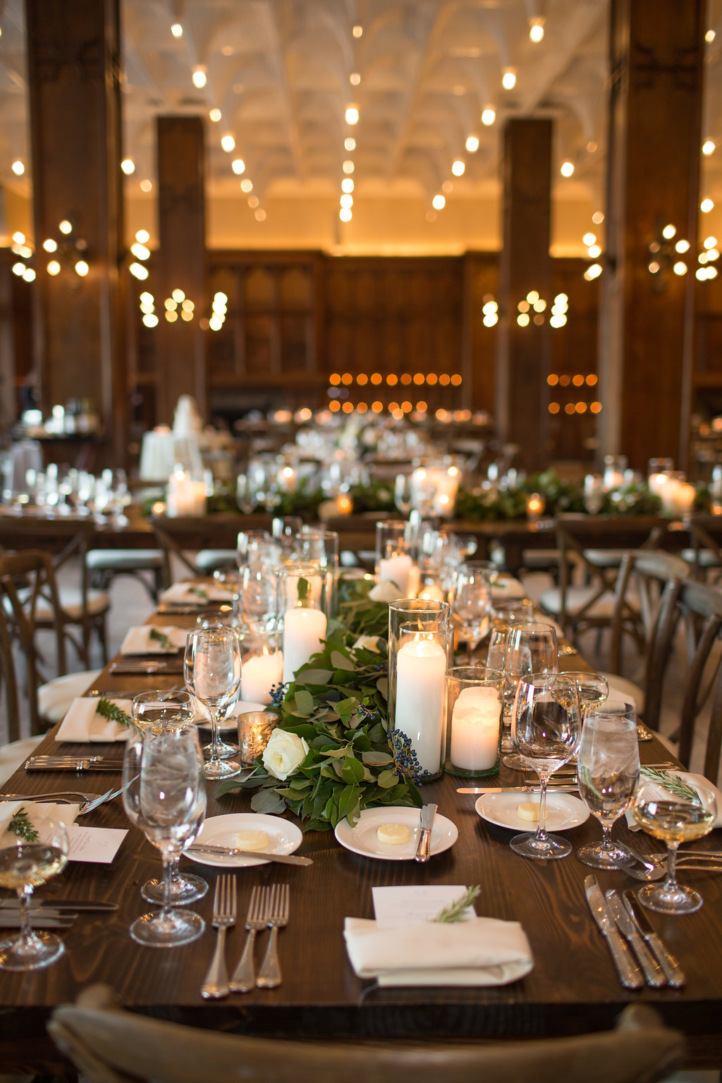 Farm tables with garlands and candles at a wedding at the Chicago Athletic Association's White City Ballroom.