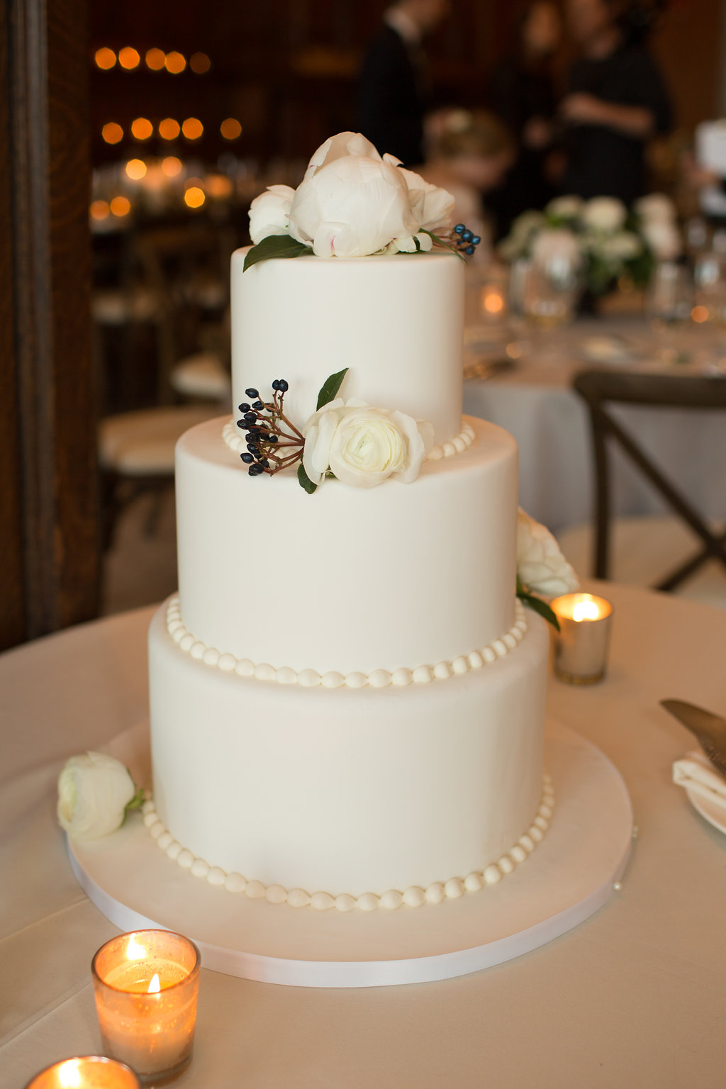 Classic ivory wedding cake ranunculus and navy berries.