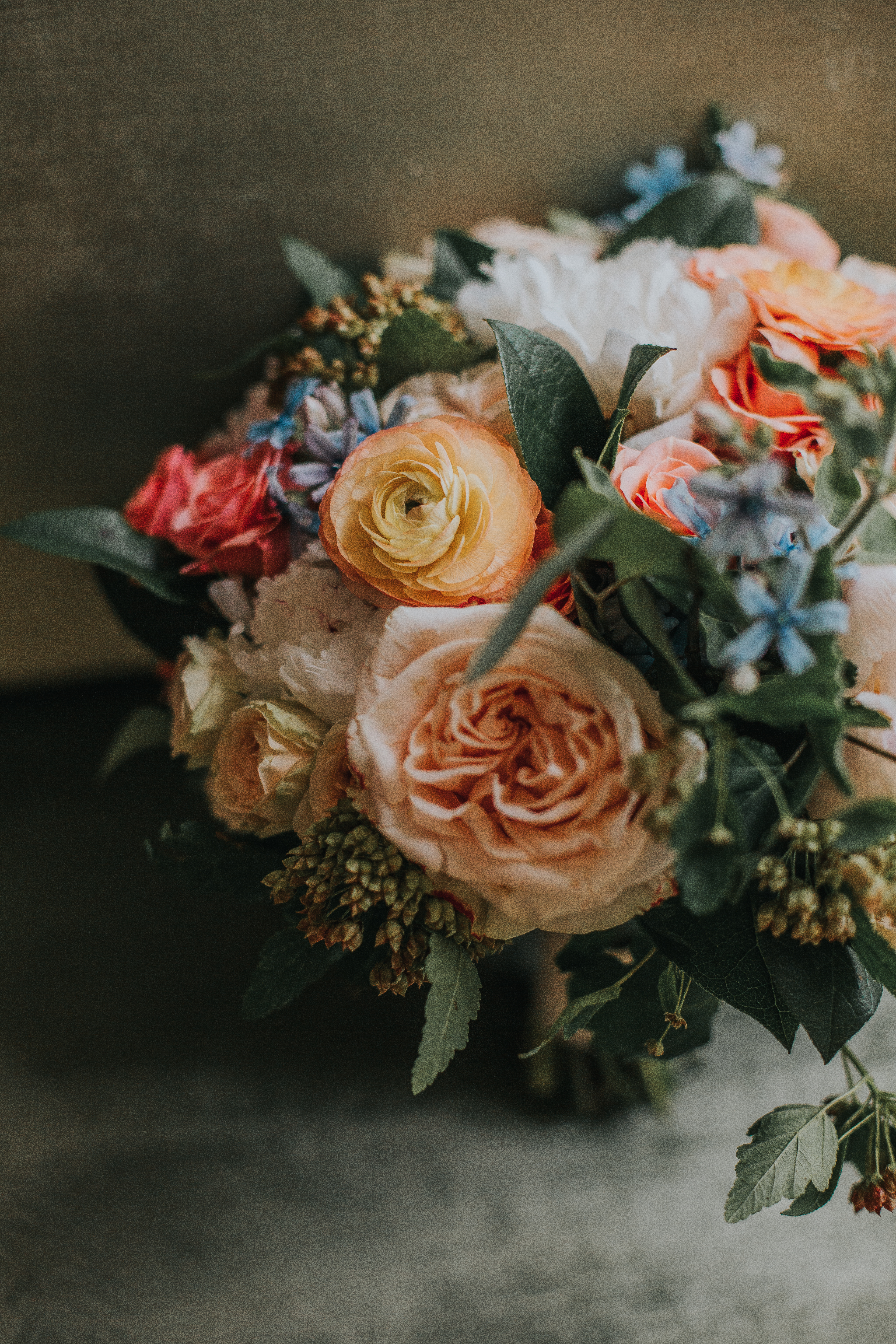 Bridal bouquet vintage style with orange ranunculus, peach garden roses, and tweedia.