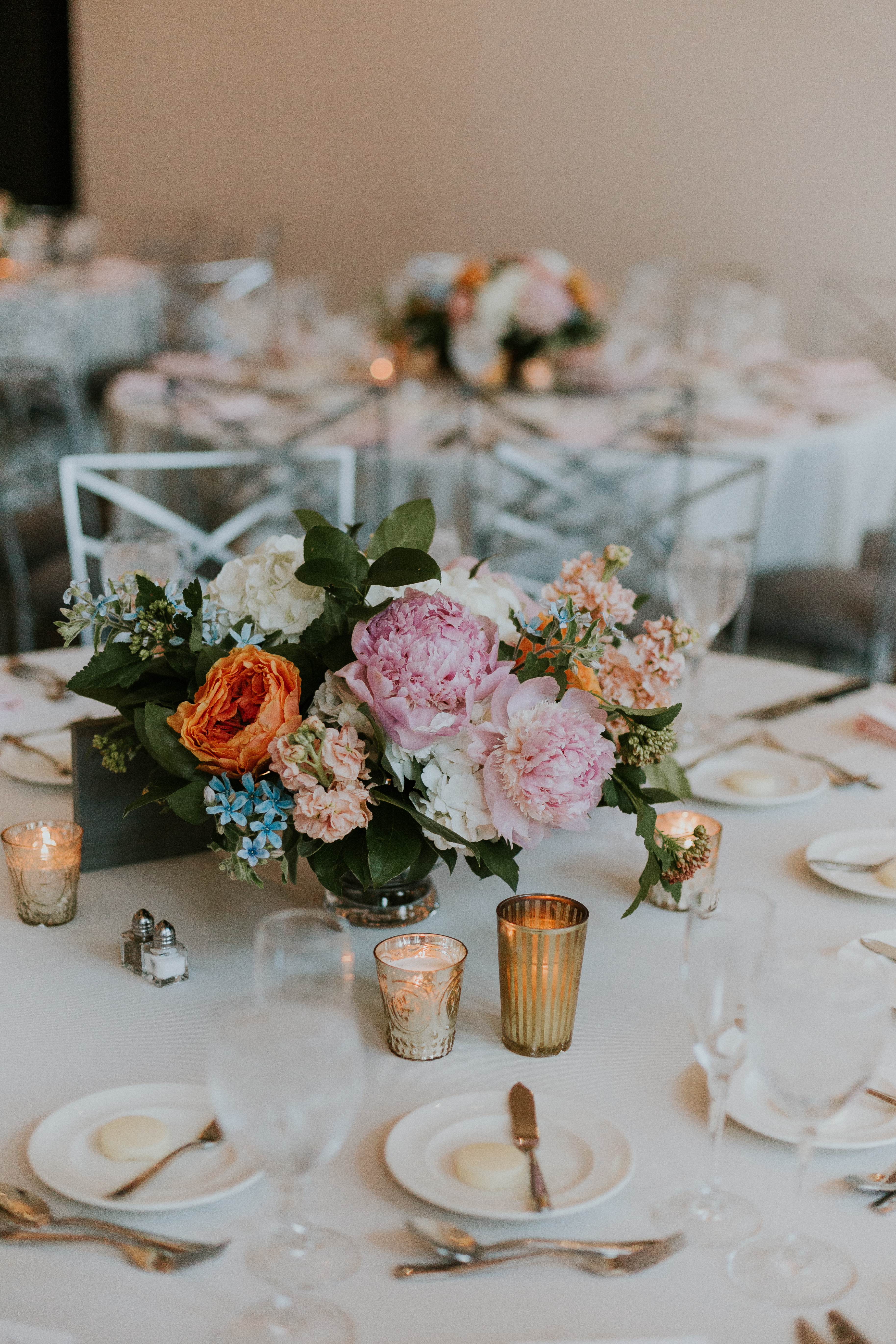 Lush summer wedding centerpieces with orange roses, pink peonies, stock, and tweedia.