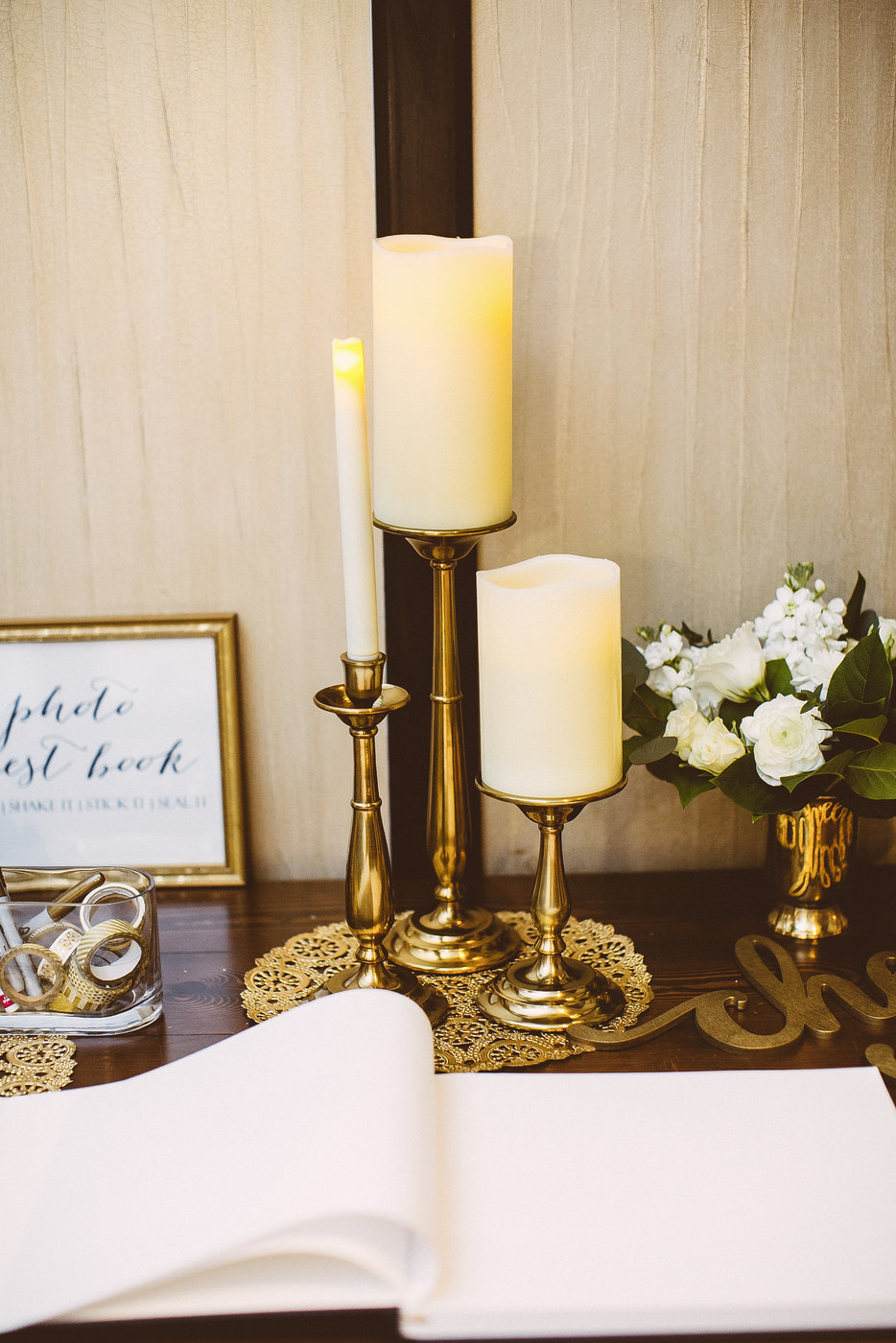 Welcome table details of vintage inspired brass candle holders and miniature monchromatic arrangements.