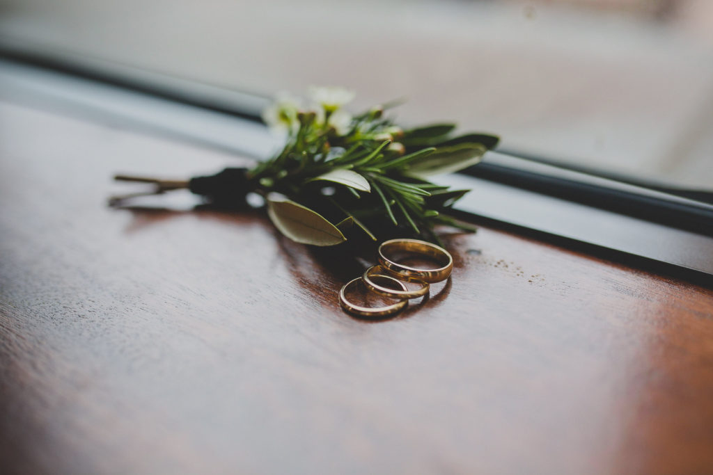 Winter wedding boutonniere with wax flowers and rosemary, wrapped with a black velvet ribbon.