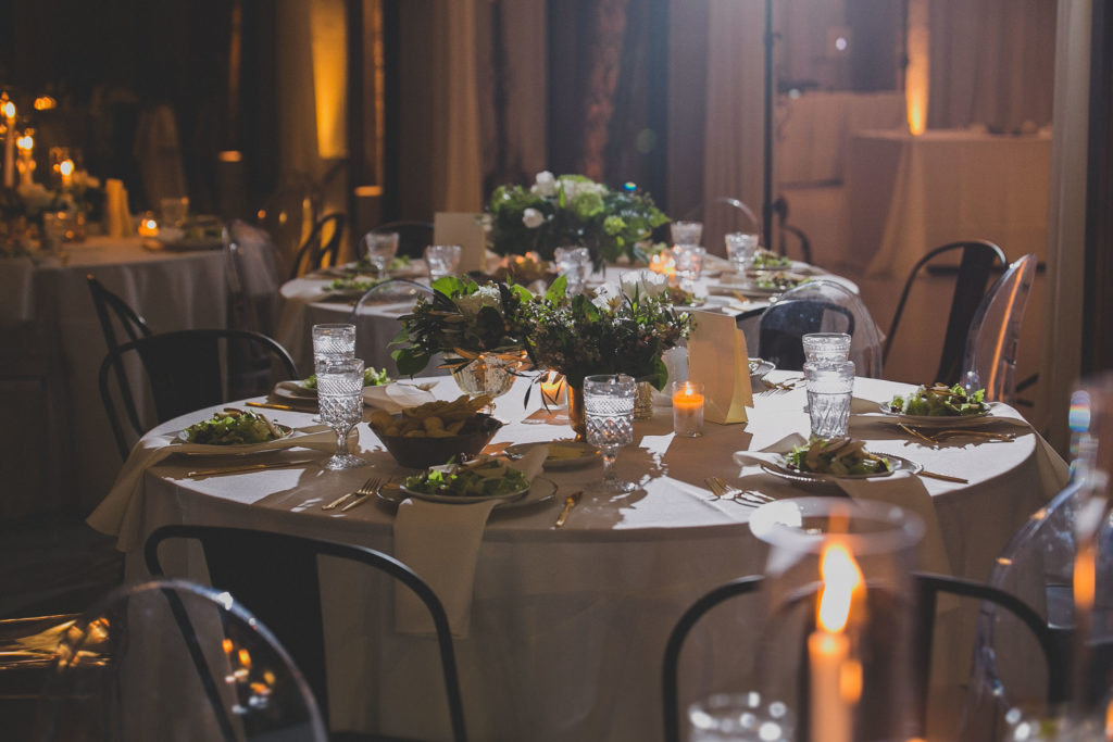 Winter wedding reception at Architectural Artifacts, with green and white arrangements of tulips, ferns, and wax flowers in mercury glass vases.