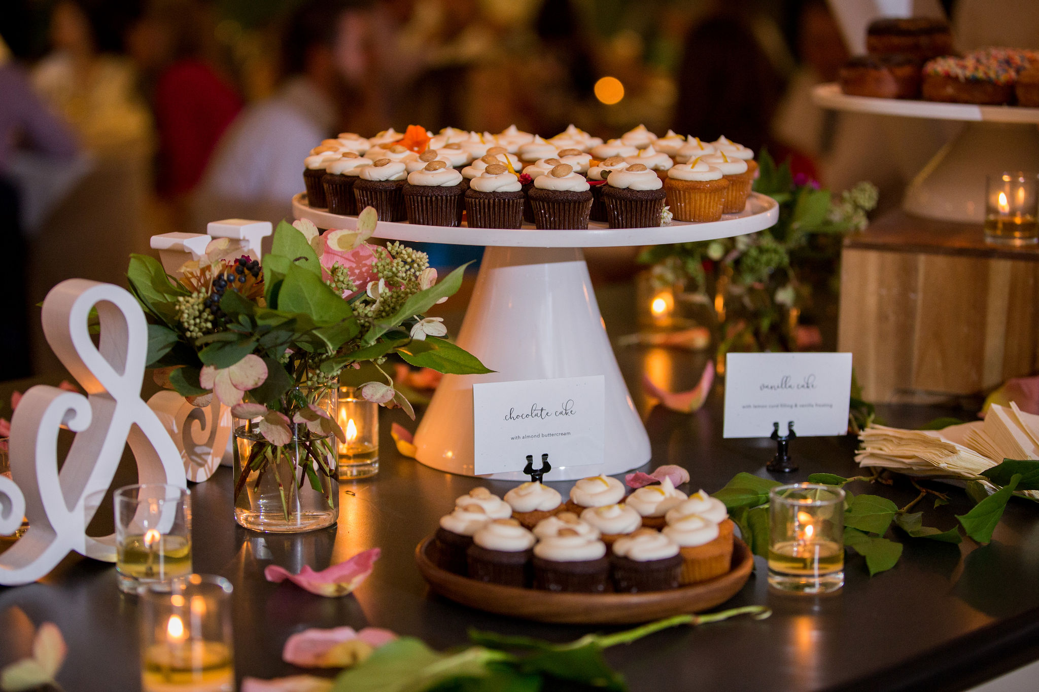 Greenhouse Loft summer wedding reception with small arrangements of pink garden roses, votive candles, and cupcakes.