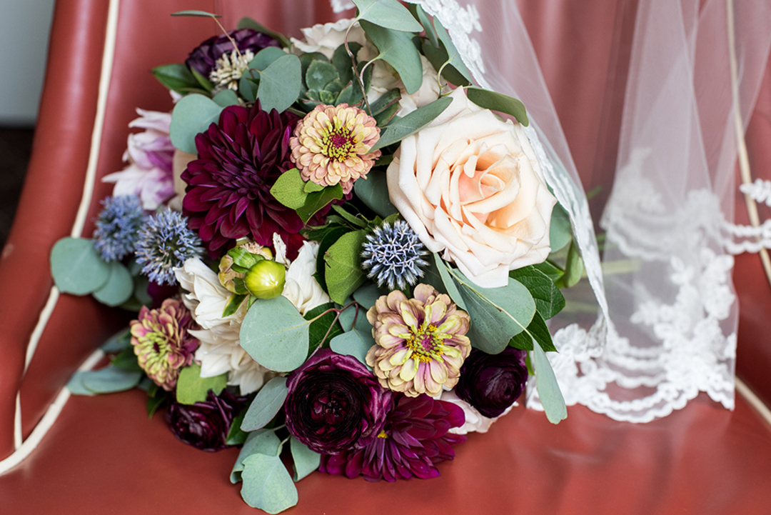 Summer wedding bridal bouquet with pink zinnias, ivory dahlias, plum ranunculus, and eucalyptus.