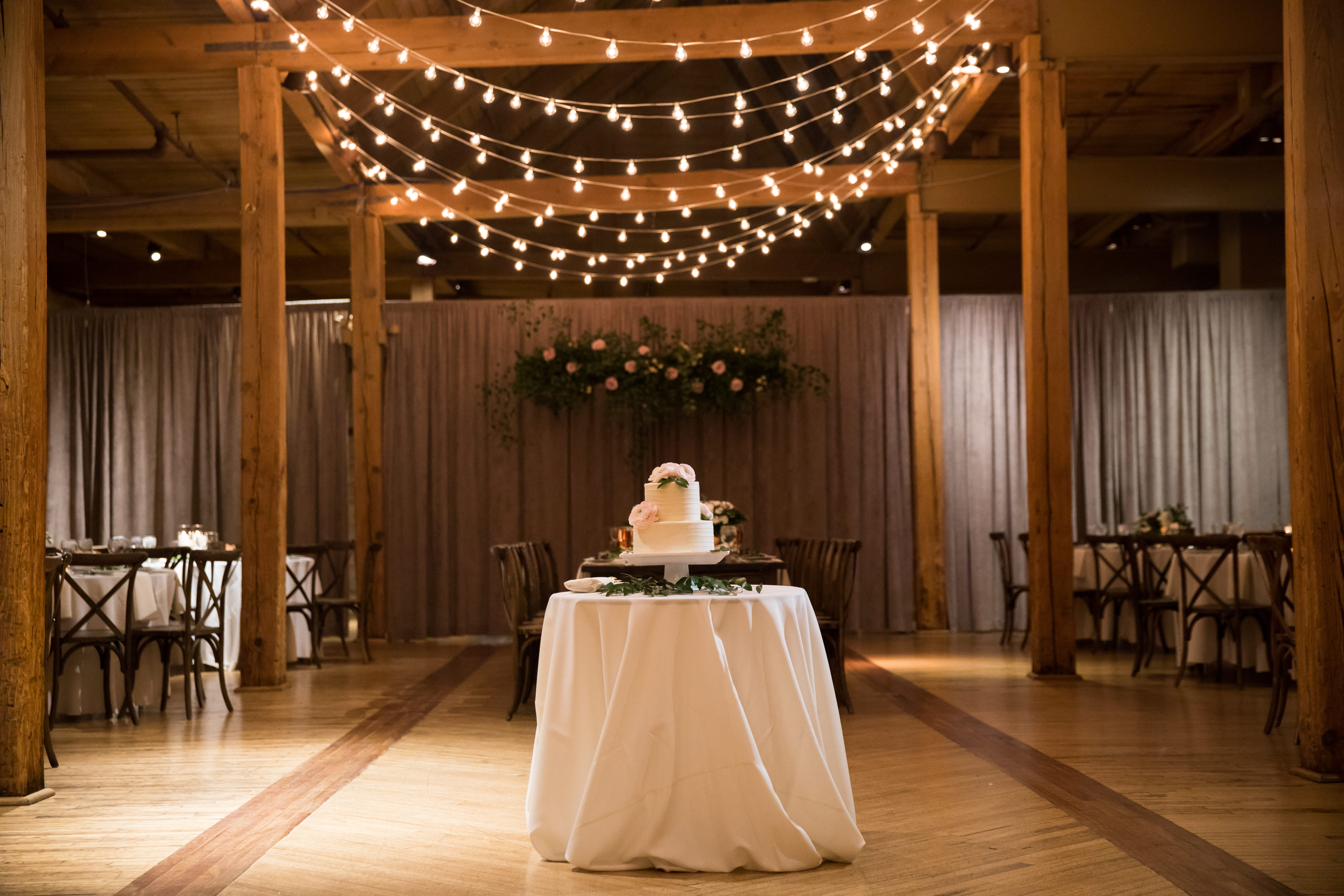 Winter wedding cake with blush ranunculus and string lights at Bridgeport Art Center Skyline Loft.
