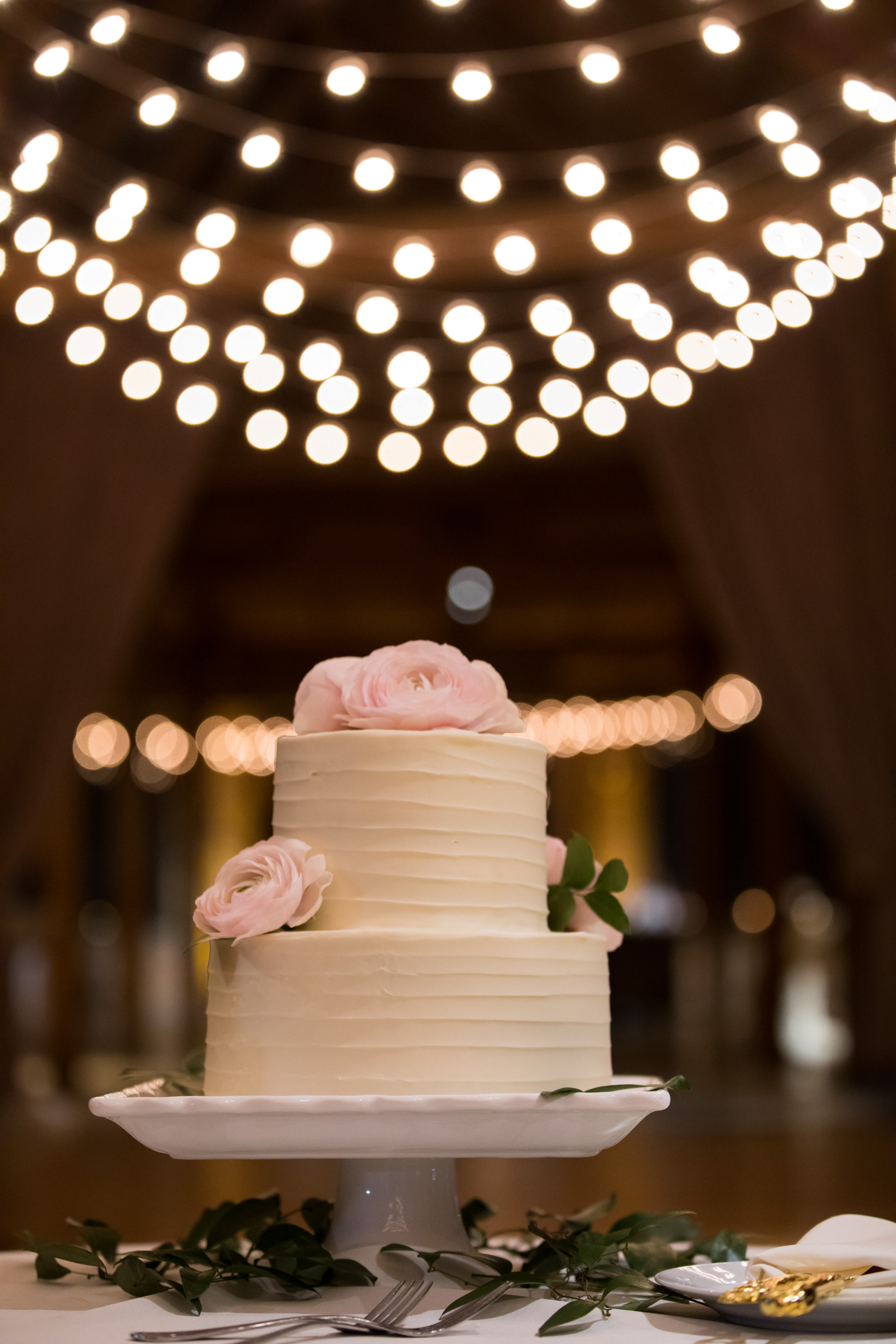 Winter wedding cake with blush Hanoi ranunculus and string lights at Bridgeport Art Center Skyline Loft.