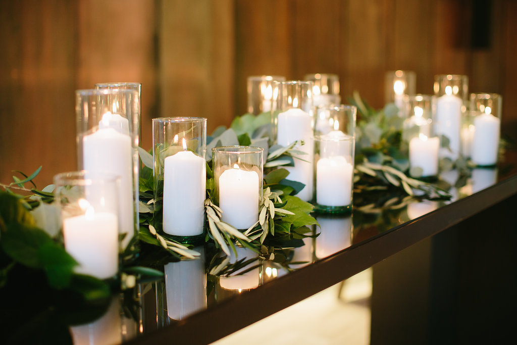 Olive foliage with pillar candles for a minimalist winter wedding ceremony backdrop.