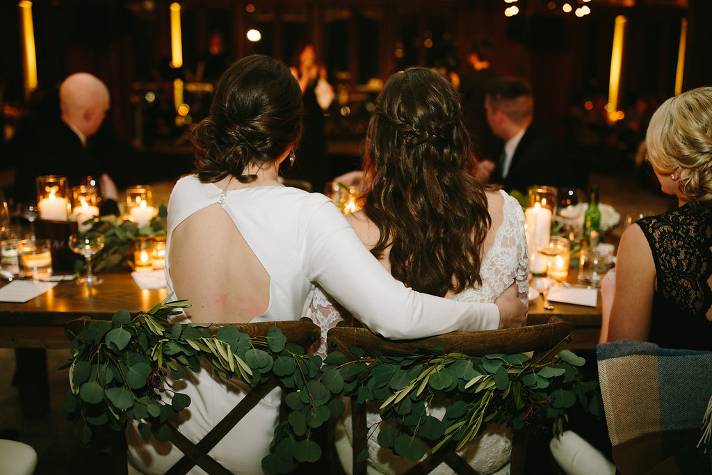 Olive foliage and silver dollar eucalyptus decorated wooden chairs for brides at Chicago Athletic Association winter wedding.