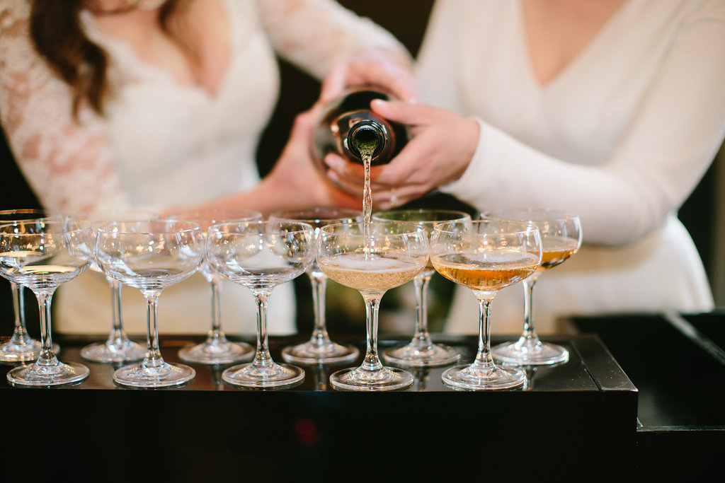 Brides pouring champagne for winter wedding toast.
