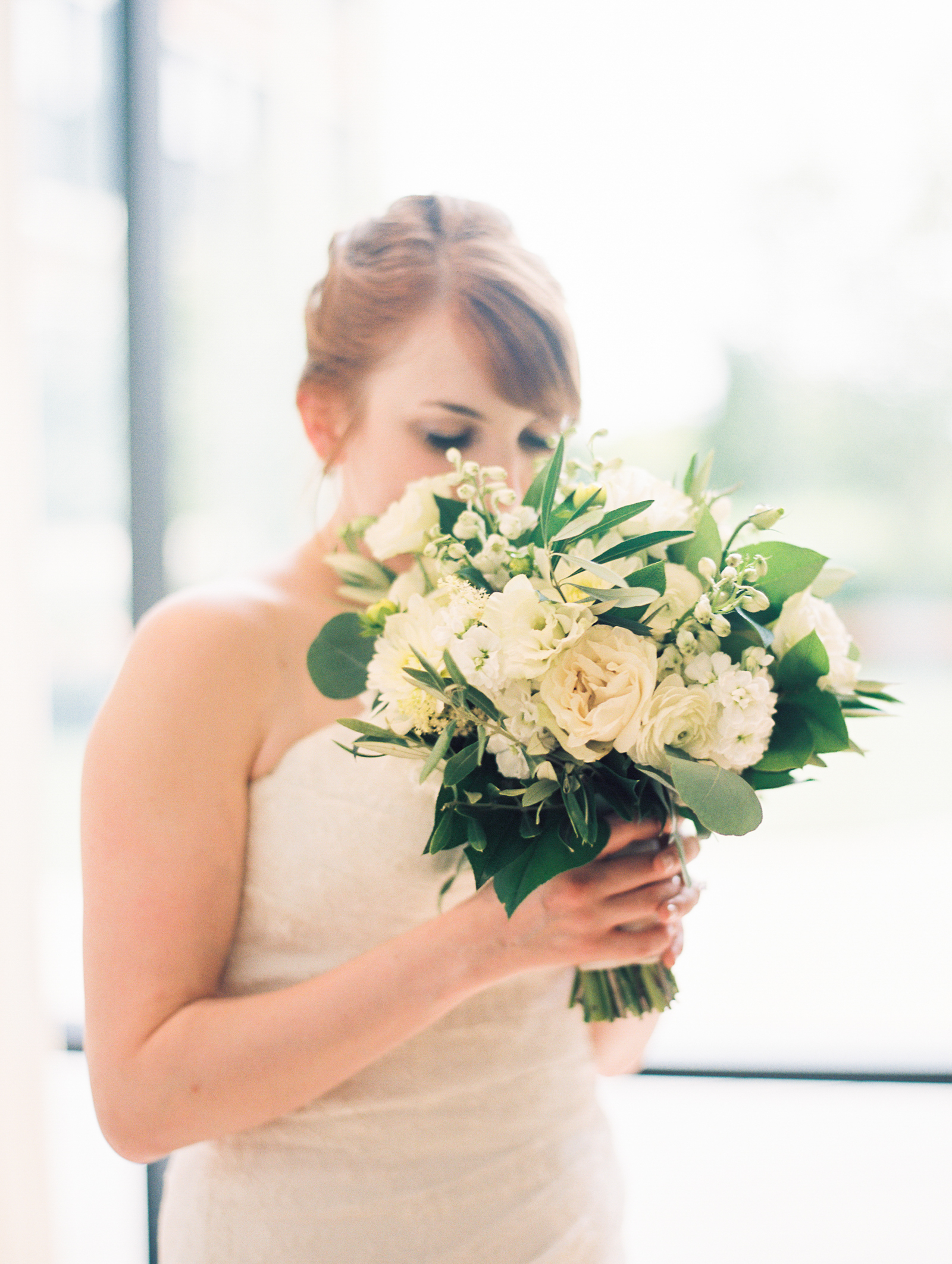 Minimalist and monochromatic fresh wedding bouquet of white dahlias, eucalyptus, ranunculus, and lisianthus.