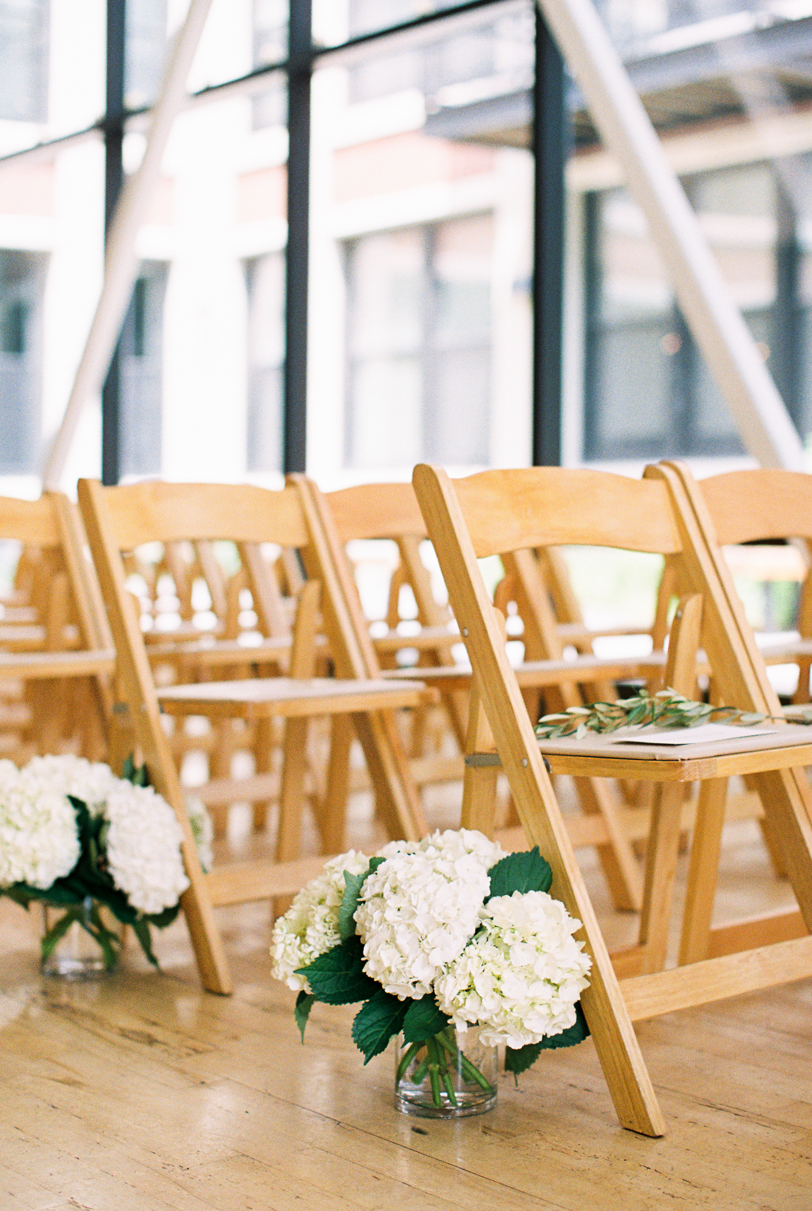 Minimalist and monochromatic Greenhouse Loft wedding ceremony with white hydrangea and eucalyptus.