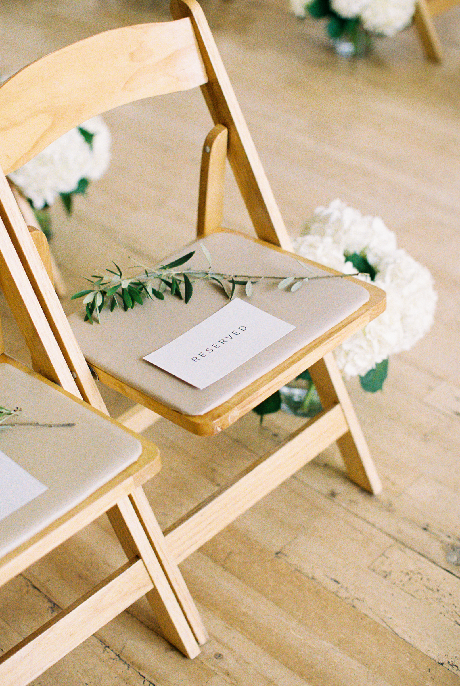 Minimalist and monochromatic Greenhouse Loft wedding ceremony with white hydrangea and sprig of eucalyptus.