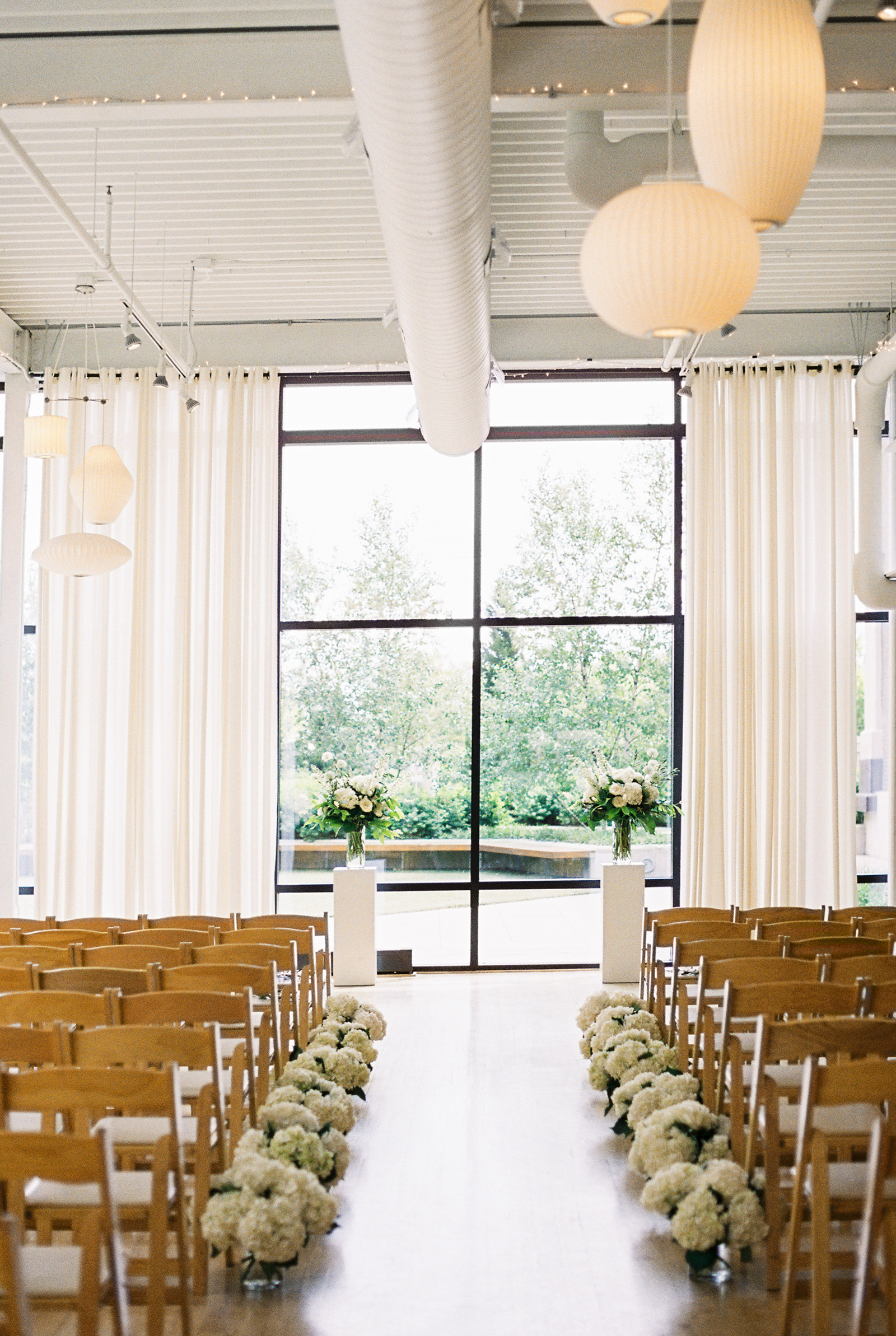 Minimalist and monochromatic Greenhouse Loft wedding ceremony with white hydrangea and altar flowers.