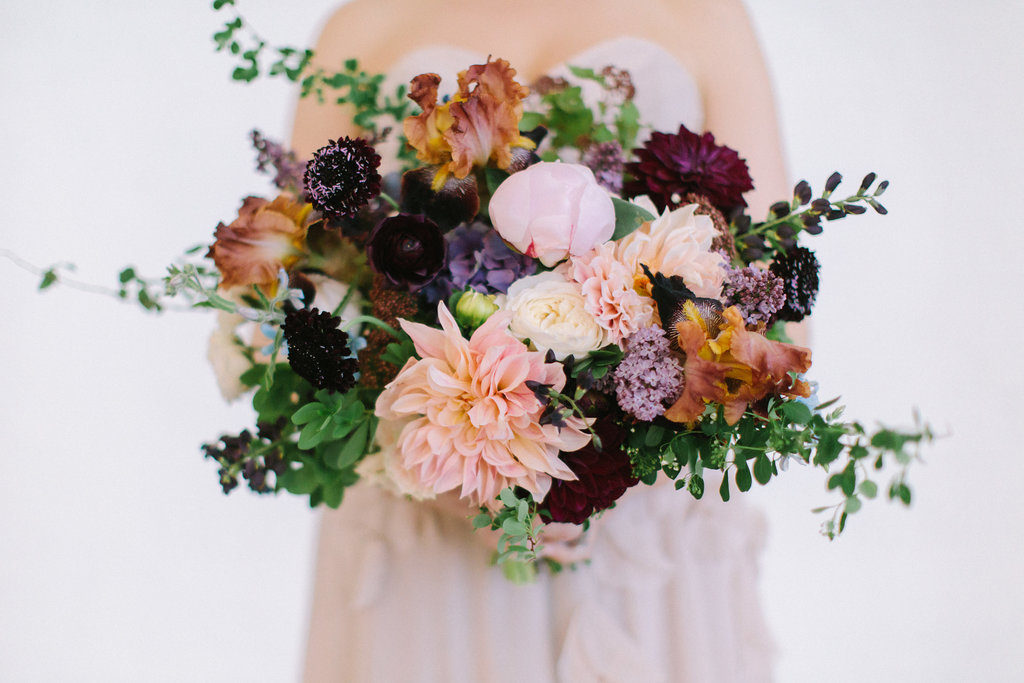 Bridal bouquet with pink dahlia and peonies, irises, plum scabiosa, berries, tweedia, and lilac.