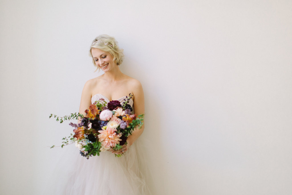 Bride in champagne dress with gardeny bouquet of pink dahlia and peonies, irises, plum scabiosa, hydrangea, berries, tweedia, and lilac.