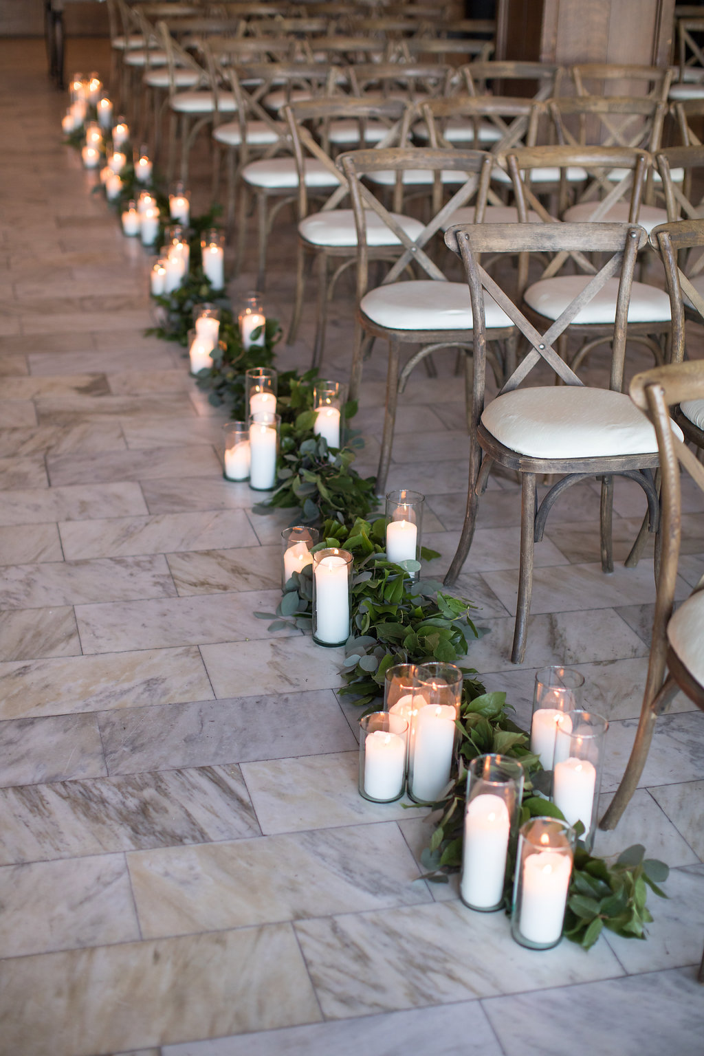 Wedding ceremony aisle with foliage garland and candles at Chicago Athletic Association. Photo by Cristina G Photography.