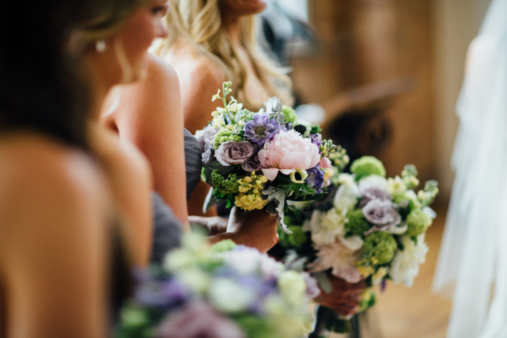 Spring bridesmaids at City View Loft Chicago with dusty purple and lime green bouquets of scabiosa, peonies, snowball viburnum, and anemones.