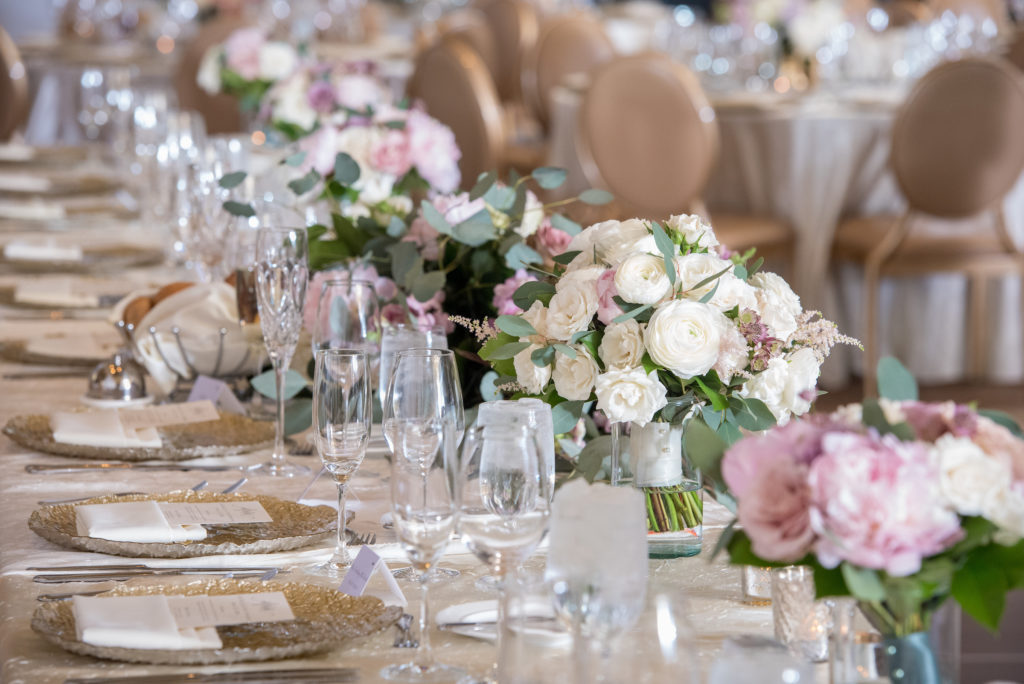 Head table with soft-toned color palette of pale pink peonies, astilbe, ivory garden roses and ranunculus, and sage green eucalyptus for a gold and ivory spring wedding reception.