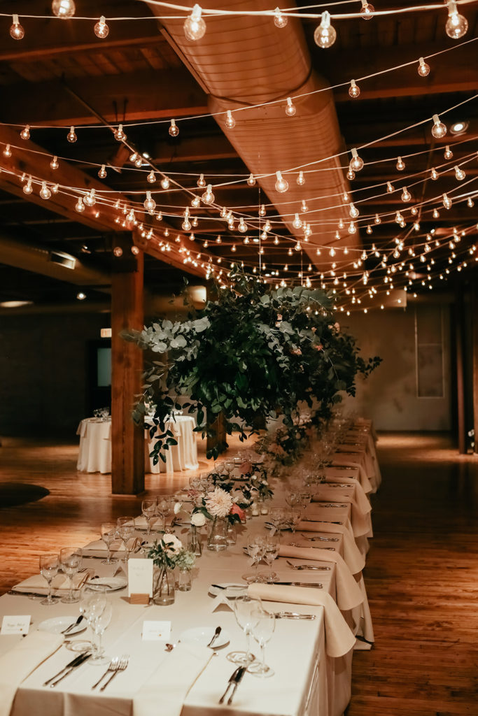 Bridgeport Art Center's Skyline Loft in Chicago wedding reception with hanging floral installation and cafe lights over head table with blush dahlias. 