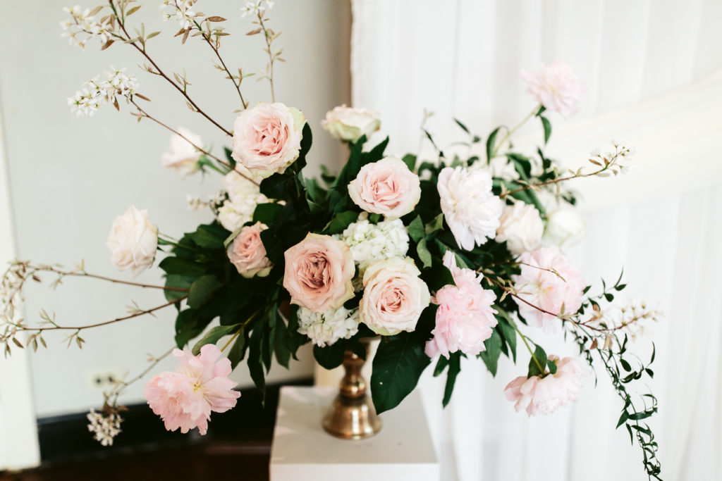 Altar arrangements on pedestals with flowering branches add interest to to the composition with garden roses, pink peonies, and hydrangea. 