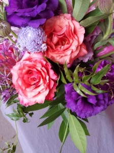 Bouquet in purple, orange, and pink, with Dark Milva roses, purple lisianthus, scabiosa, allium, and jasmine.